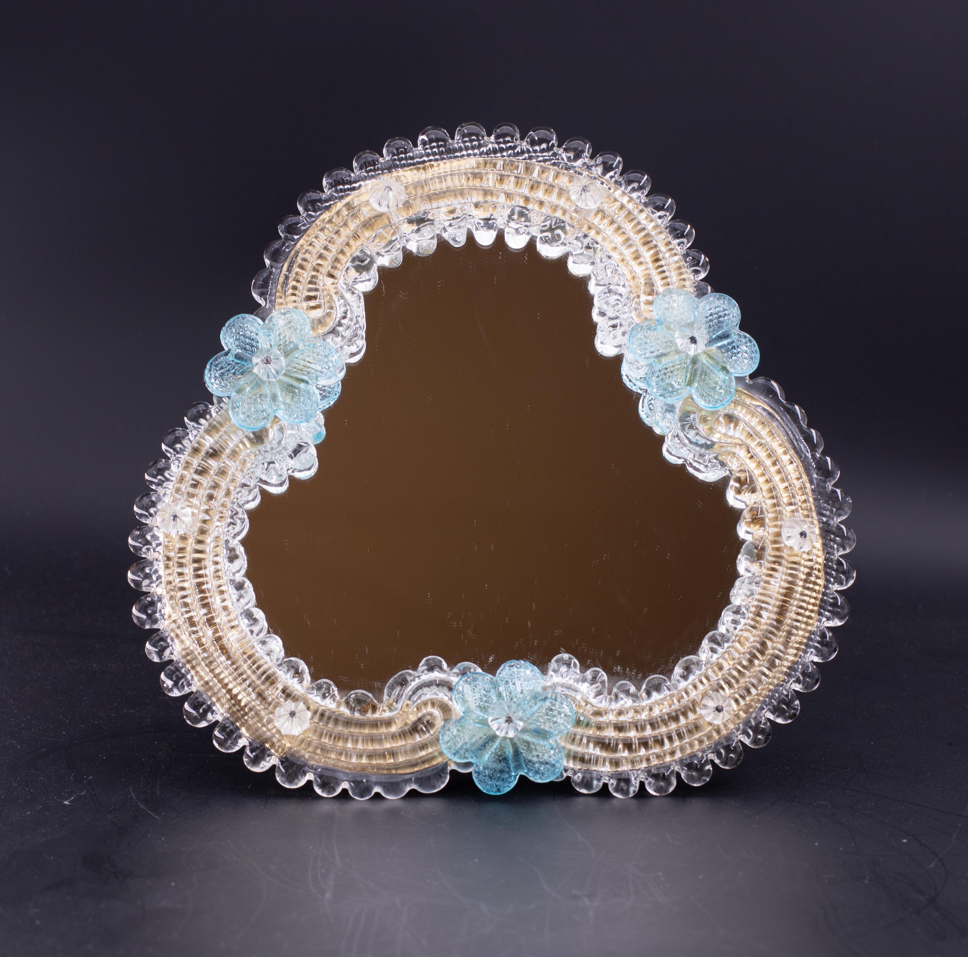 Specchio classico veneziano con lavorazione tipica di Murano.

Lo specchio è decorato con 3 tipici fiori azzurri.

Eccellenti condizioni vintage.

Altezza 18 centimetri, larghezza 21 centimetri.