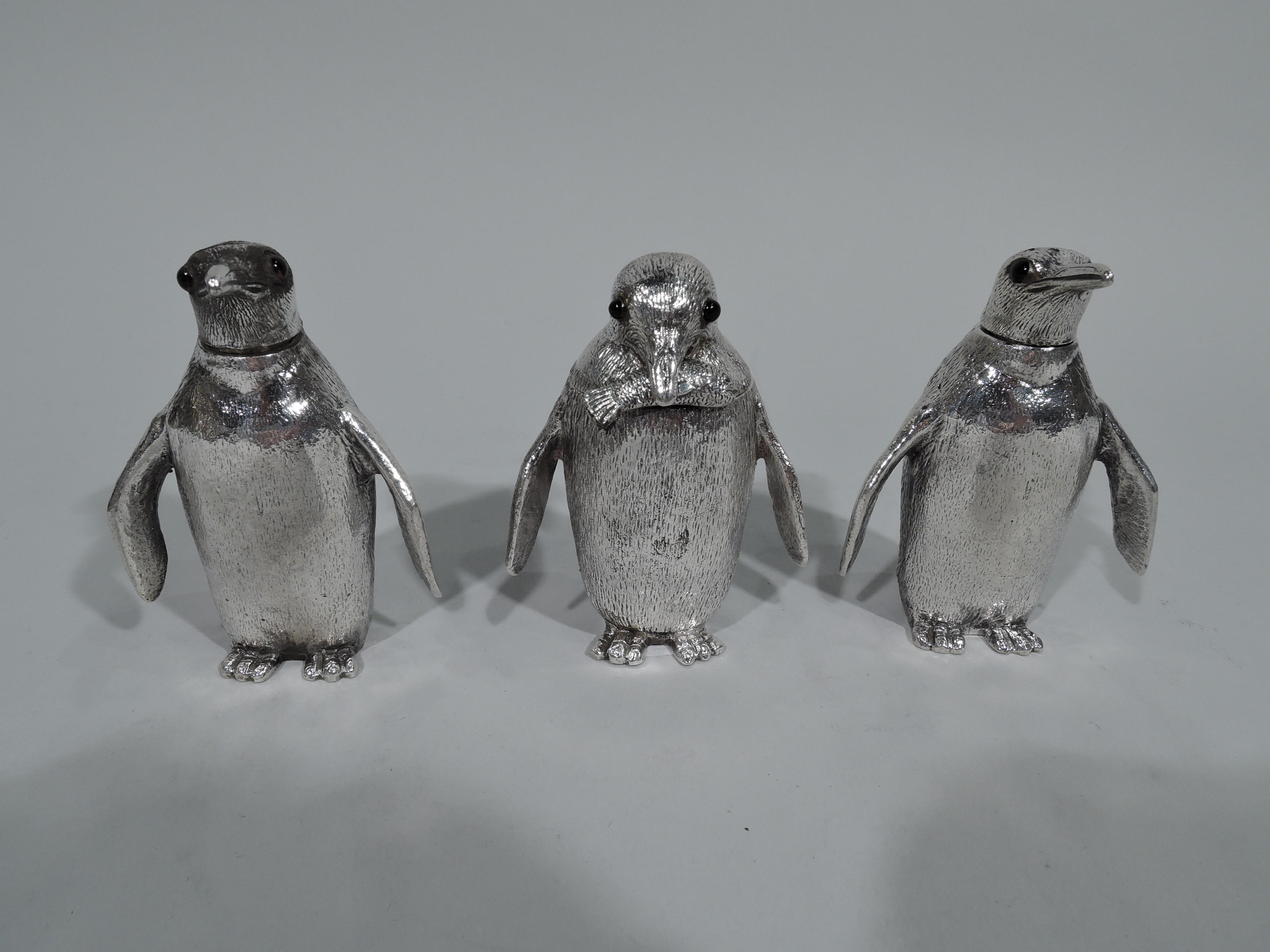 Classic penguin sterling silver condiment set. Made by Alfred Dunhill in London. There are three waddling birds with striated feathers, stumpy wings, webbed feet, and beady glass eyes. Two are salt and pepper shakers with pierced and detachable