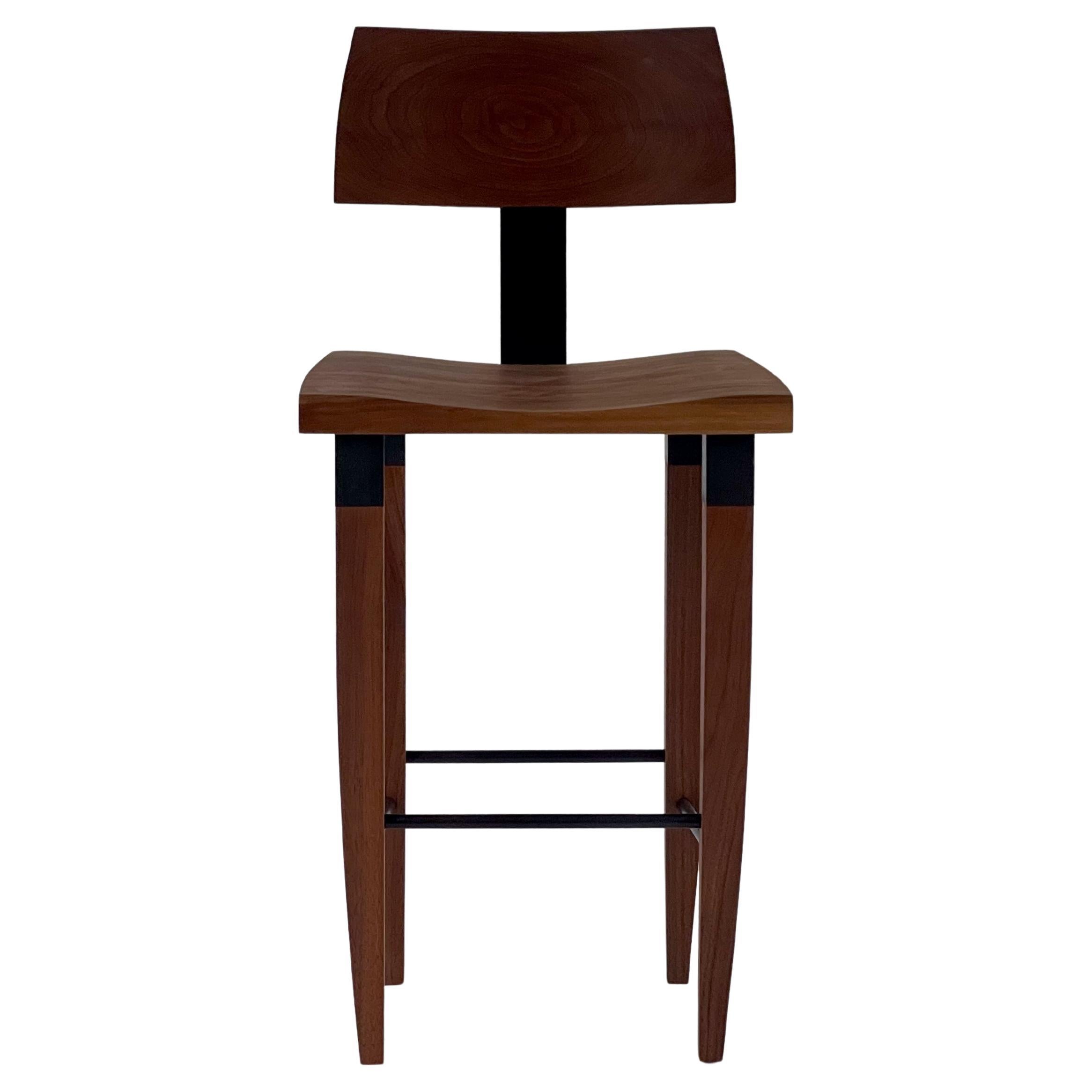 This walnut bar stool is based on the Classic Dining Chair #2 by Chris Lehrecke, originally designed in 1994.  These have solid backs and seats in hand carved walnut. The custom made cuffs and rods are of blackened bronze. The metal back support is
