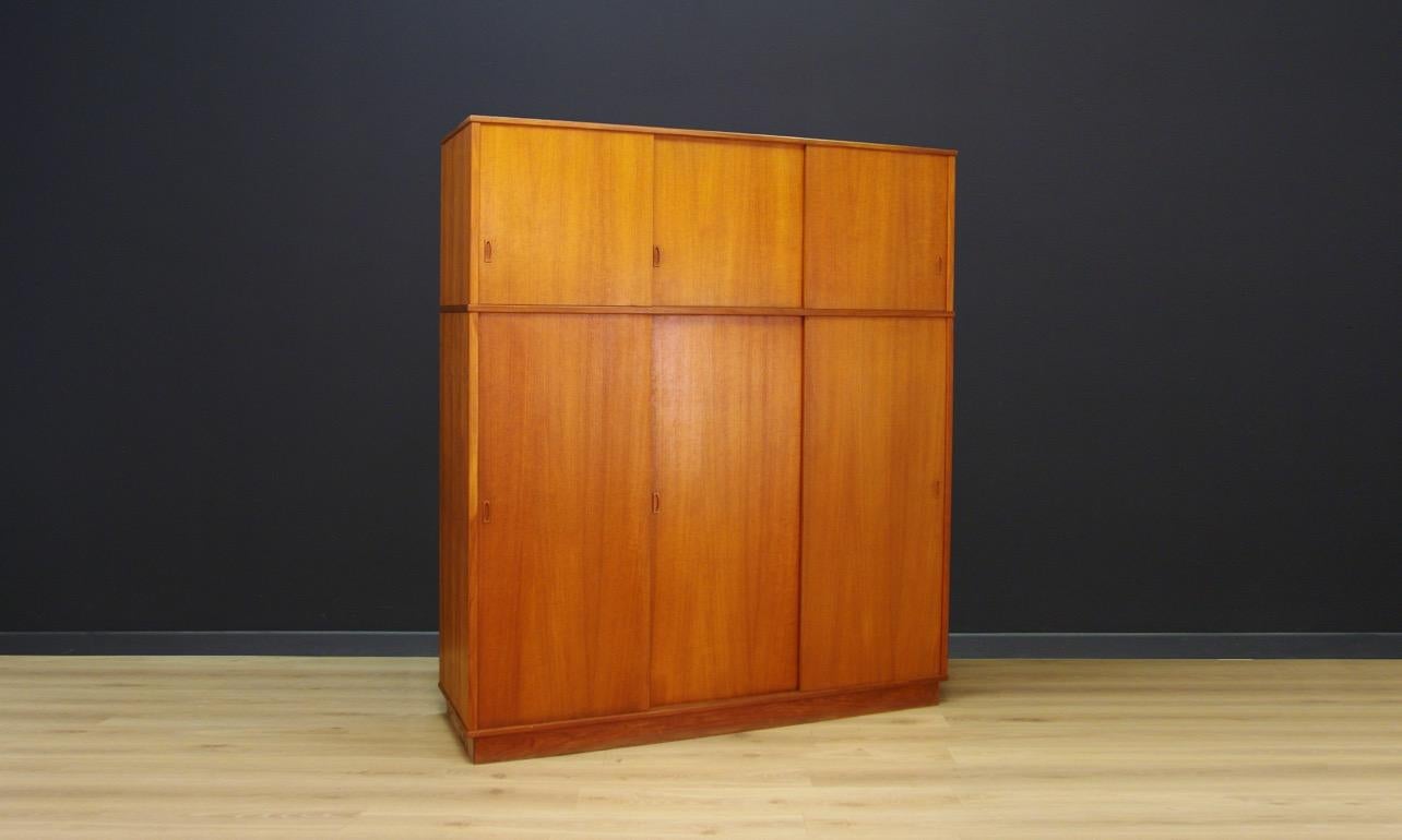 Classic wardrobe from the 1960s-1970s, minimalist form - Scandinavian design. Finished with teak veneer. Behind the sliding doors the wardrobe has shelves, two drawers, and a roomy space. Preserved in good condition (visible small dings and