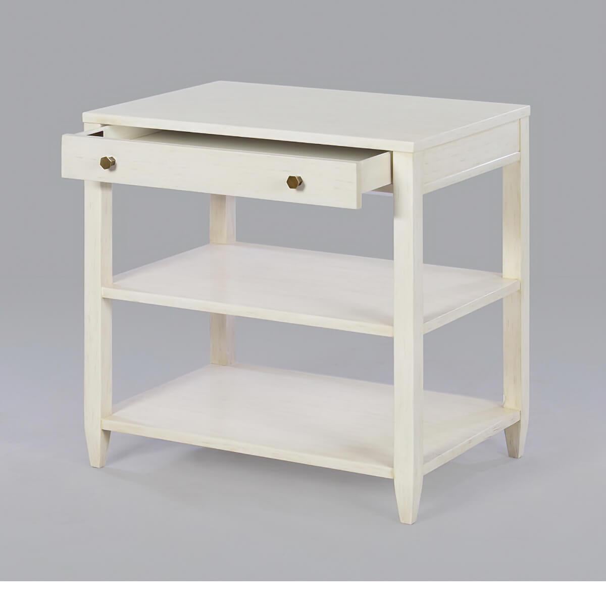 Classic wide rectangle side table with a drawer, two shelves, brass hardware, and tapered feet, has a rustic “drift” white painted finish with subtle grey distressing with subtle visual distressing and a hand-rubbed finish.

Dimensions: 26