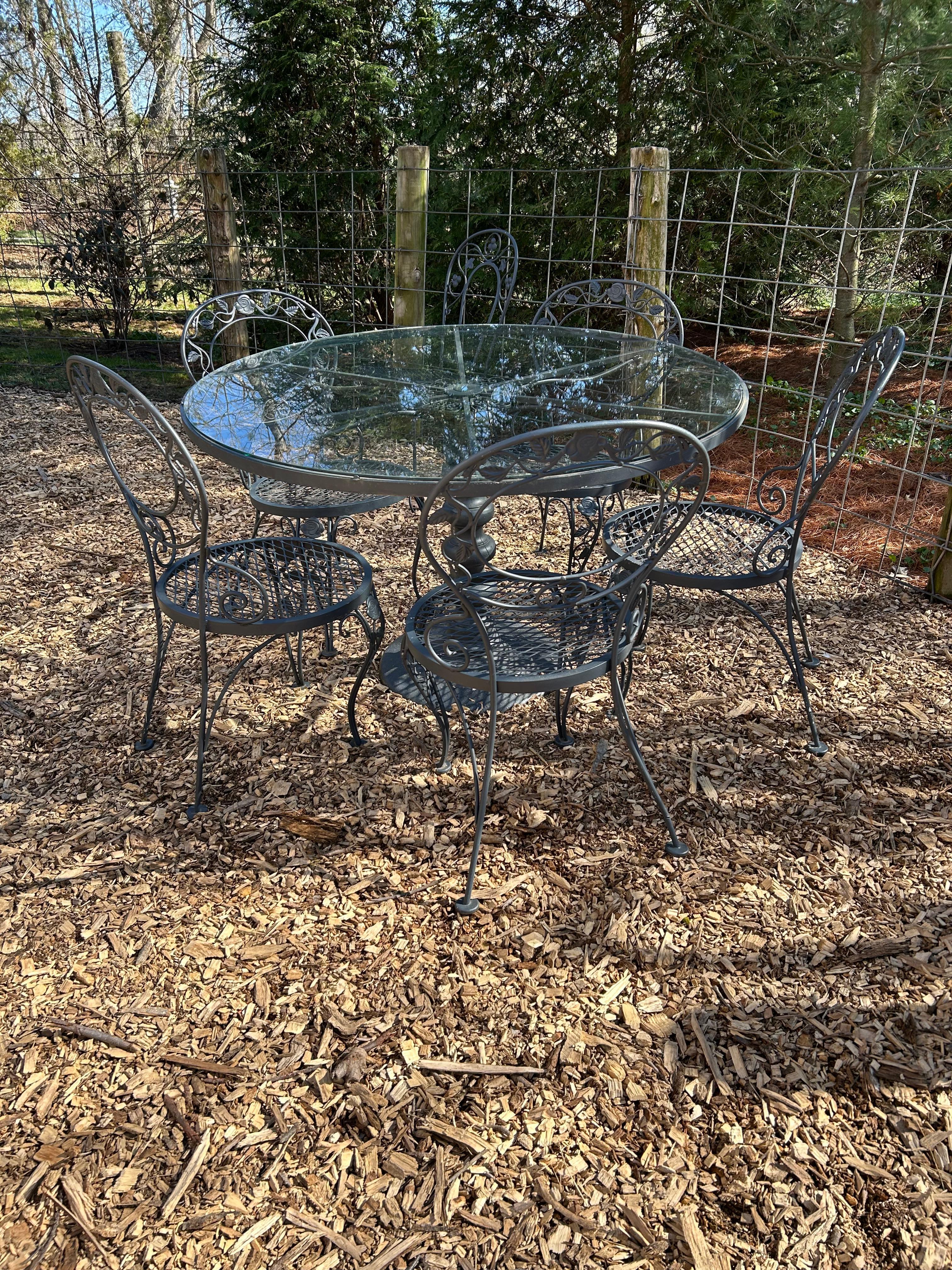 Ensemble de salle à manger d'extérieur en métal et verre de style Woodard entièrement fonctionnel comprenant une table ronde avec les dimensions ci-dessus et 5 chaises assorties. 18,25 l 33,25 h diamètre du siège 17 hauteur du siège 16,5

Solide et