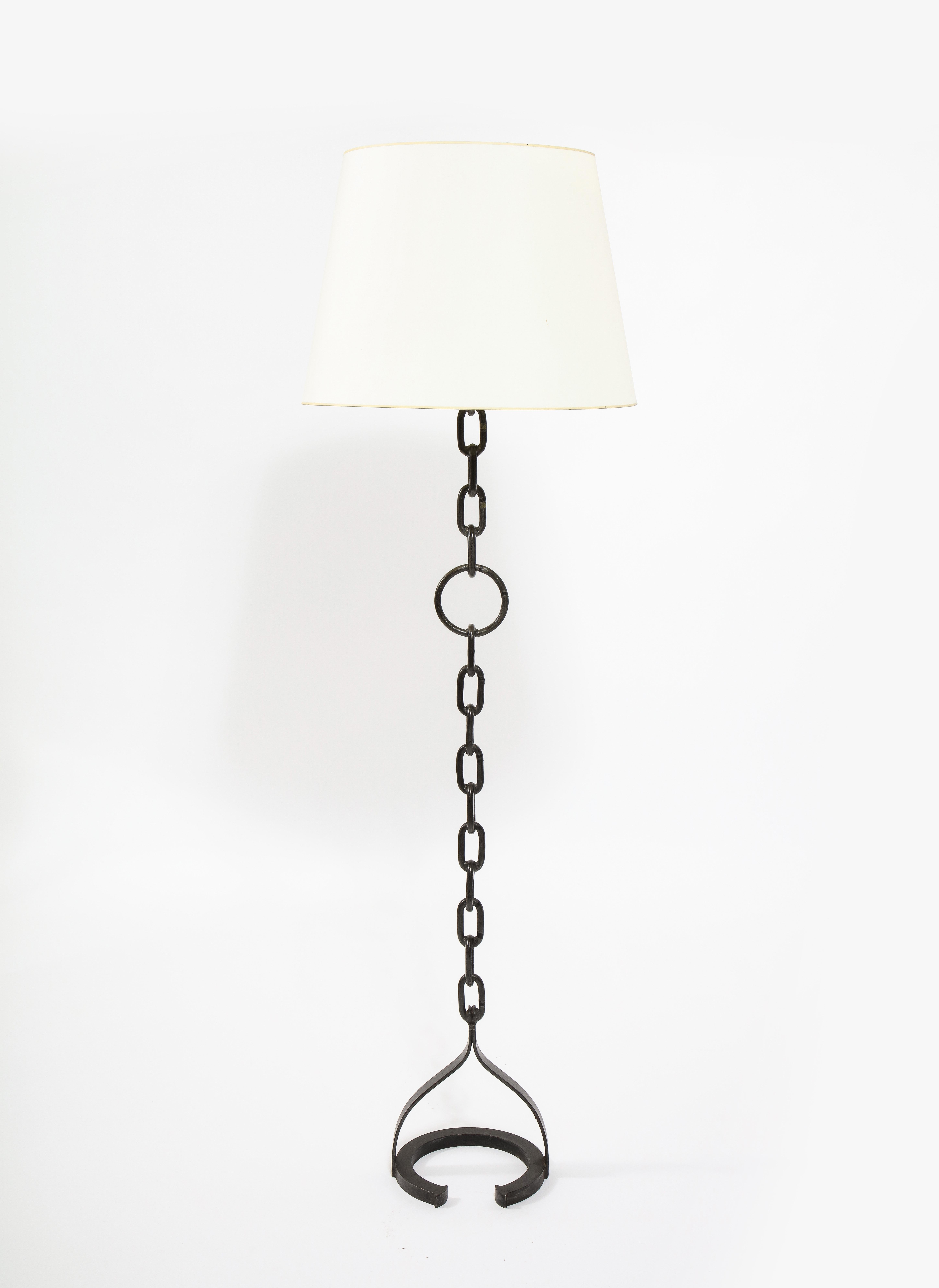 Elegant wrought iron standing lamp made of welded chain links with a large ring in the center resting on a half-round base. Shade is not included. 

Also available, table lamp version of same.