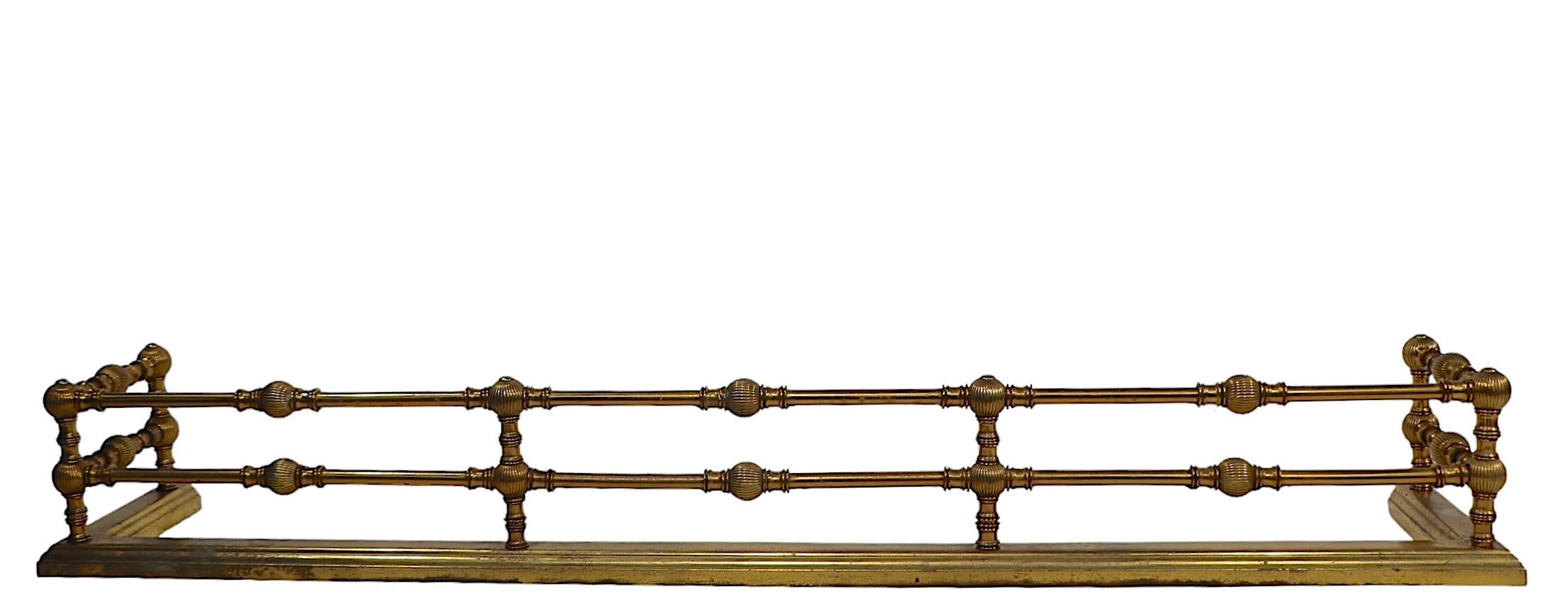 Classical Victorian,  Aesthetic Movement brass fireplace fender. The fender features two repeating brass rails, with decorative fluted ball spaces.  late 19th century vintage, this example was probably made in the USA, in the English manner, it is