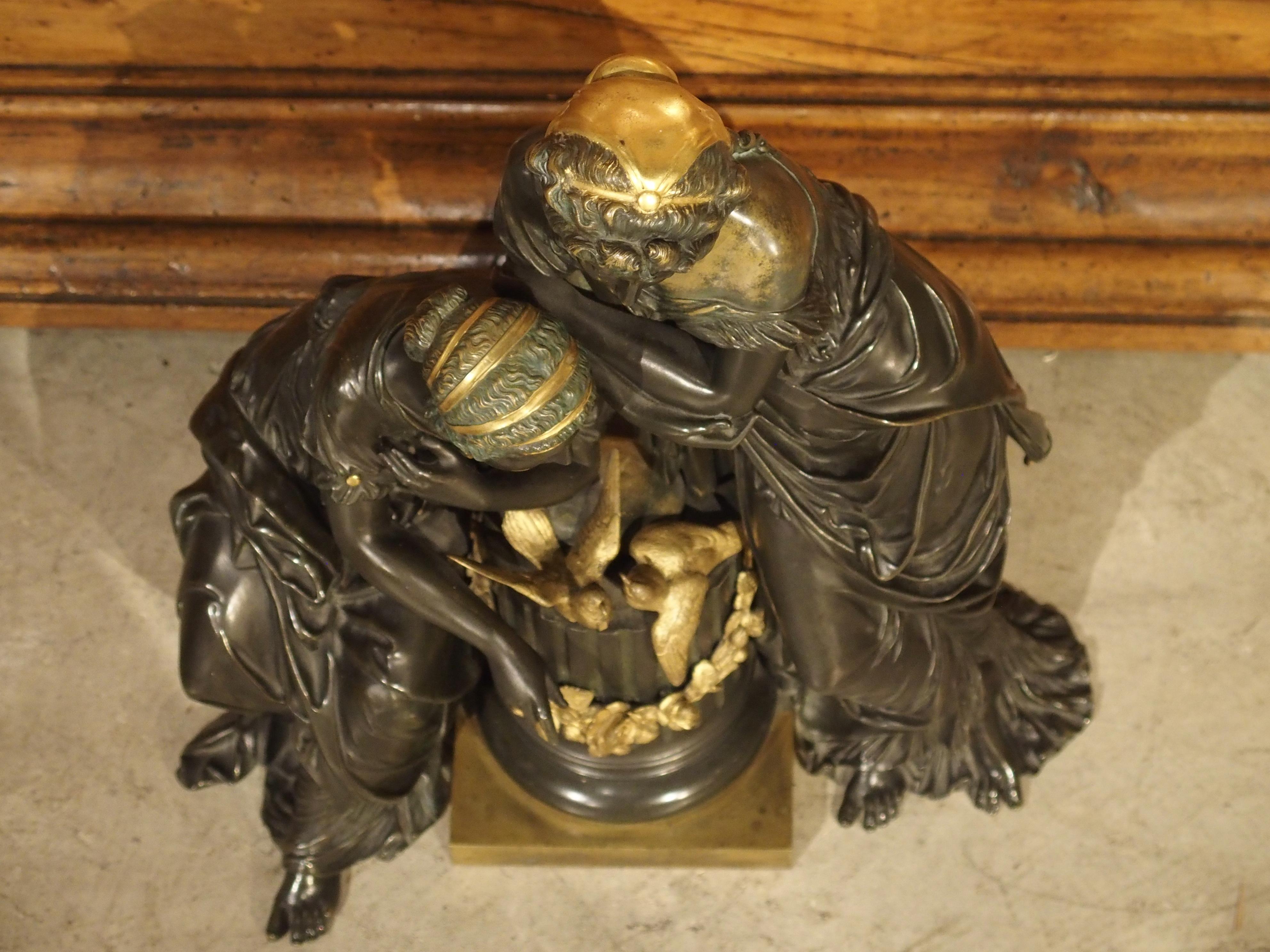 This striking black patinated bronze sculpture is offset with a few small bright sections of gold. The Classical subject matter features two maidens resting and gazing upon a fluted half column with two gold birds. It exhibits fine details and