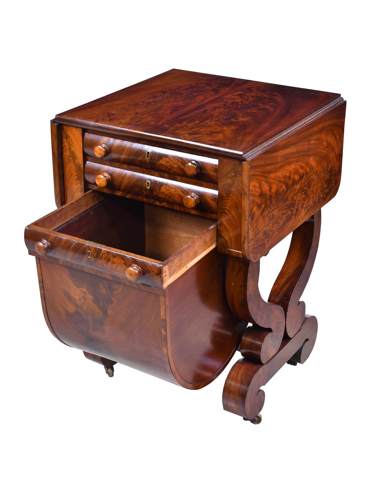 A very beautiful American Empire work table in the Grecian style in a very fine grade of solid West Indies mahogany with expert book-matching of the top planks and the crotch veneer. The top has two leaves that fold-down when not in use. The