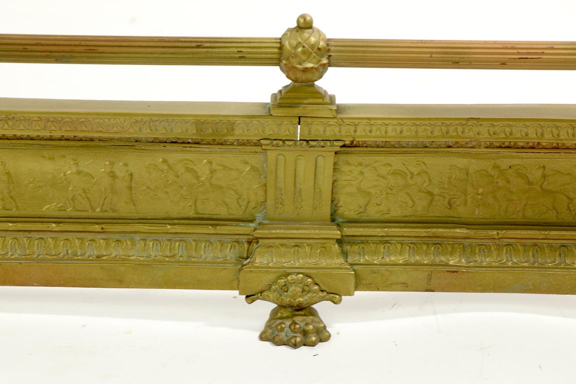 Classical brass fireplace fender having a decorative frieze depicting warriors in silhouette, fluted rail and post corners. We believe the width has been altered to make it a bit shorter. Very fine quality castings, well constructed, clean and ready