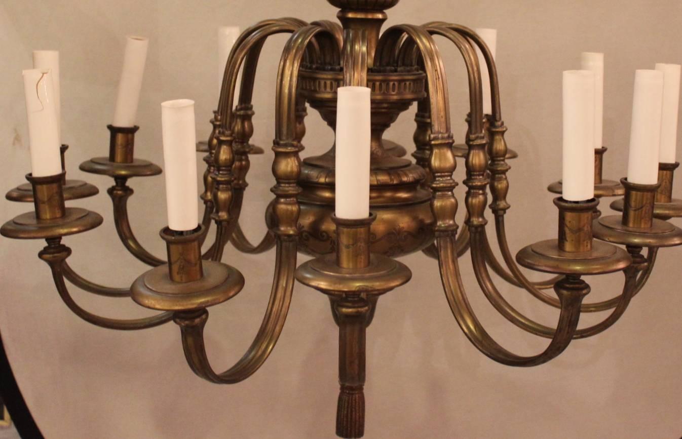 Nicely styled twelve-light patinated cast brass chandelier. Urn top with graceful sloping arms, bulbous centre.