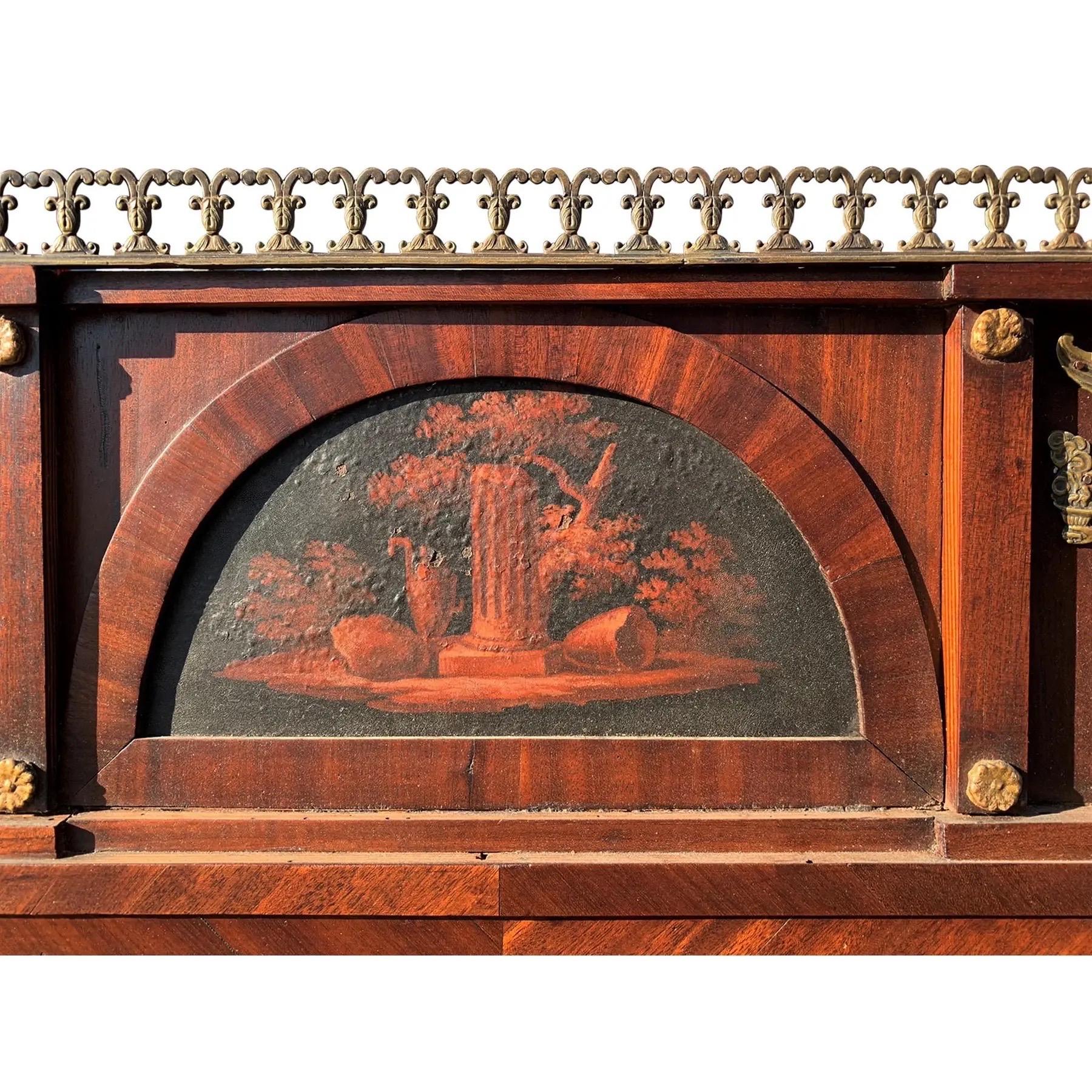 Espejo de recibidor clásico con ornamentación de madera dorada y bronce. La parte superior está decorada con una galería de bronce perforada. En el centro, un óleo sobre tabla abovedado representa una escena clásica de bosque. El espejo está