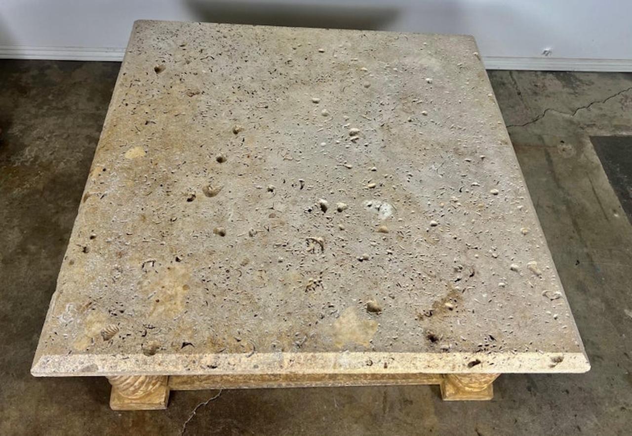 Late 20th century Italian Neoclassical style coffee table.  The table stands on four twisted wood straight legs.  The wood base has a beautiful crackled finish.  The limestone top has indentations of shells throughout.  It is a beautiful large scale