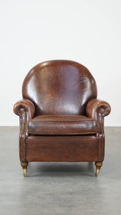 Classical, dark sheep leather armchair in good condition and on wheels