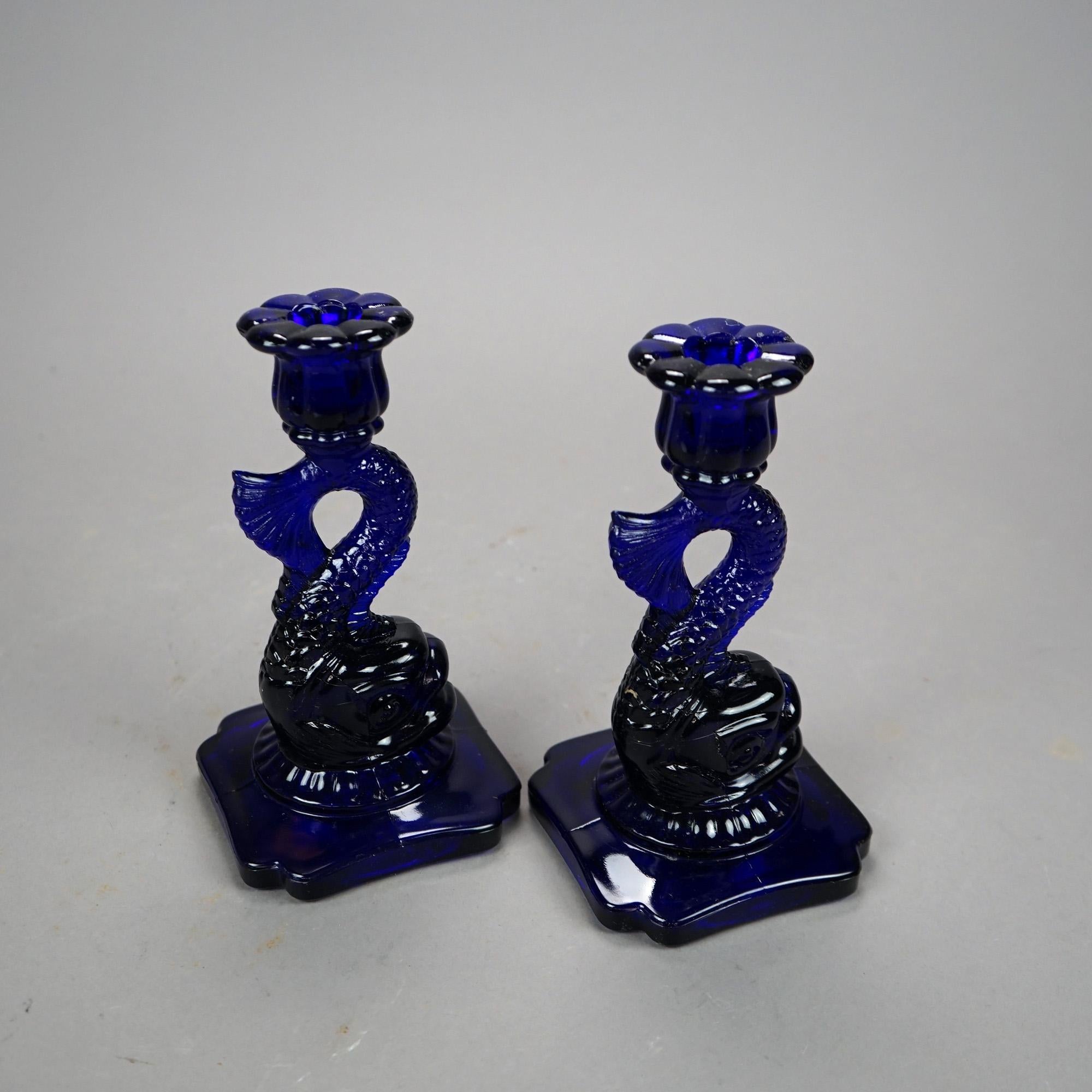 A pair of figural candlesticks offer molded cobalt art glass construction in dolphin form, 20th century.

Measures - 8''H x 4.5''W x 4.5''D.

Catalogue Note: Ask about DISCOUNTED DELIVERY RATES available to most regions within 1,500 miles of New