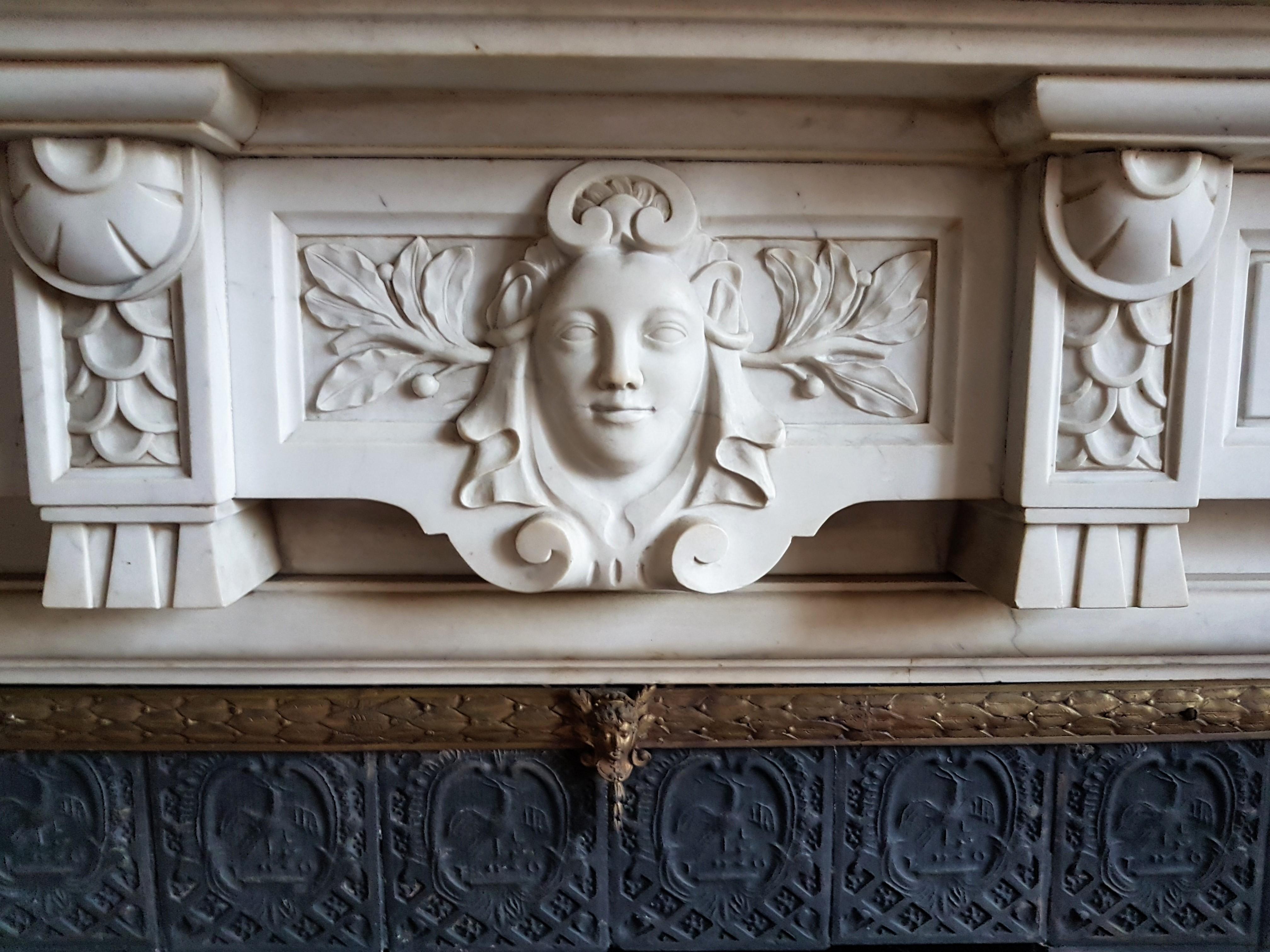 This is a sophisticated, neo-classic fireplace, made of the most soft-toned Carrara marble, named Statuary.
The breakfront frieze is centered with an elegant female-head.  This modest mantel is an example of a fireplace that brings a great sense
of