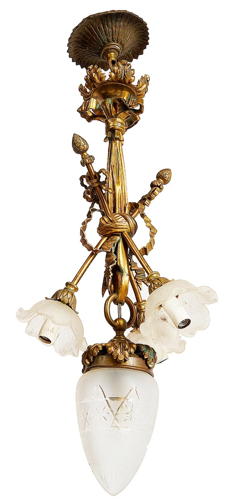 A good quality French classical late 19th century ormolu chandelier having a foliate ceiling rose coming down to draped ribbon decoration with three branches tied and flower petal shades, a central glass shade supported by a brass ring.
