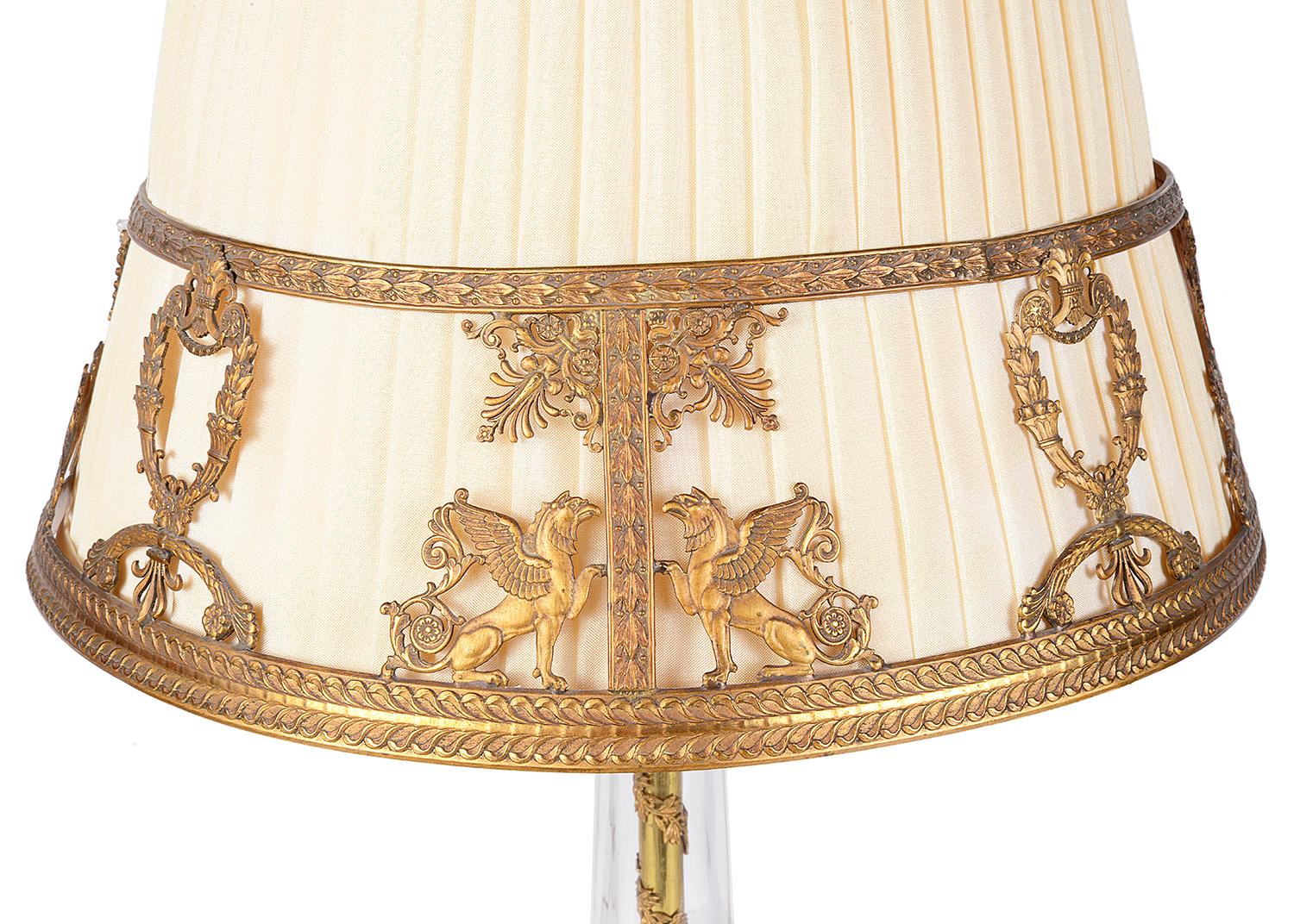A very good quality late 19th century French gilded ormolu table lamp, having a pleated shade, Empire influenced griffins, motifs and foliate decoration. The glass stem with pieced ormolu, classical maidens with children playing and mounted on a