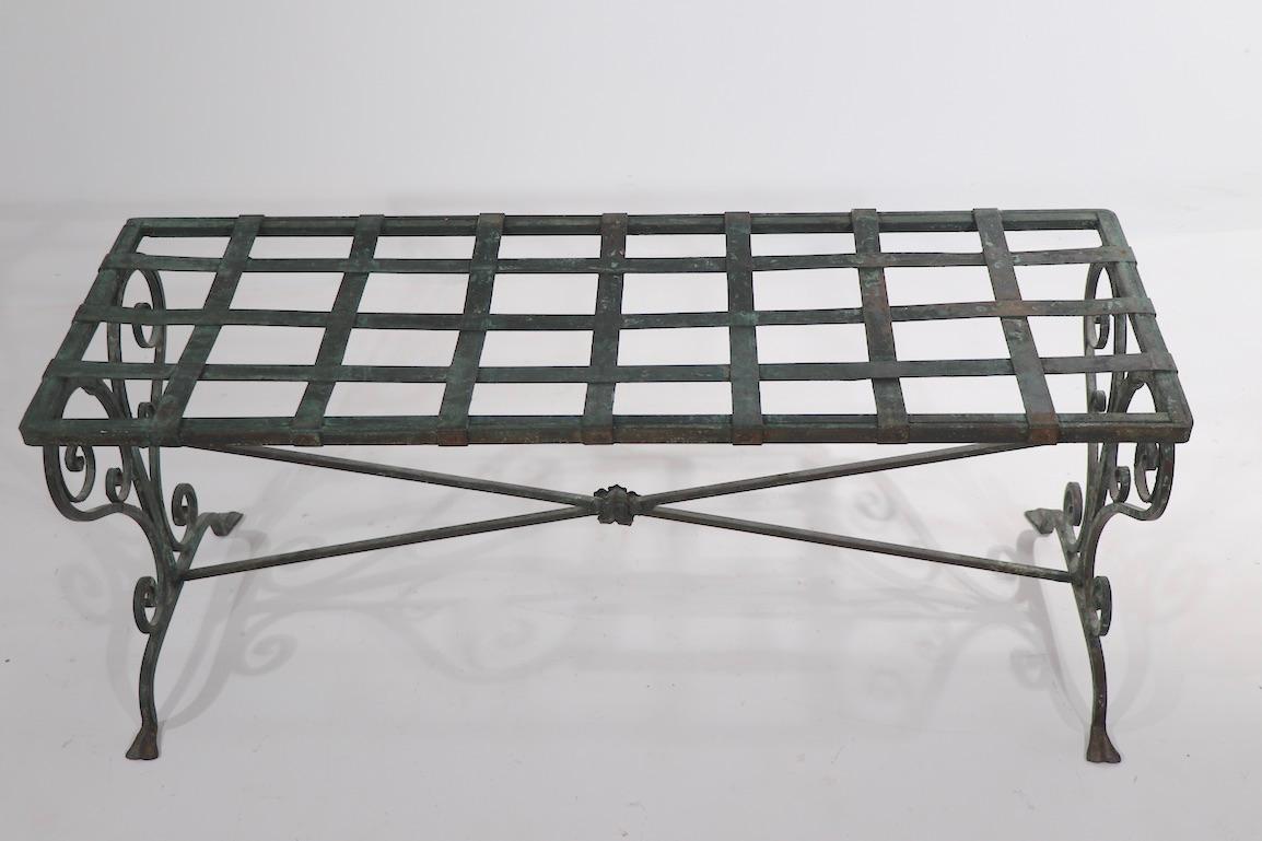 Wonderful classical style garden bench of wrought iron in a faux ver Di Gris finish. The bench has a grid pattern strap metal top, with decorative cirlicue legs. Well crafted and in great preserve, suitable for indoor or outdoor use - possibly