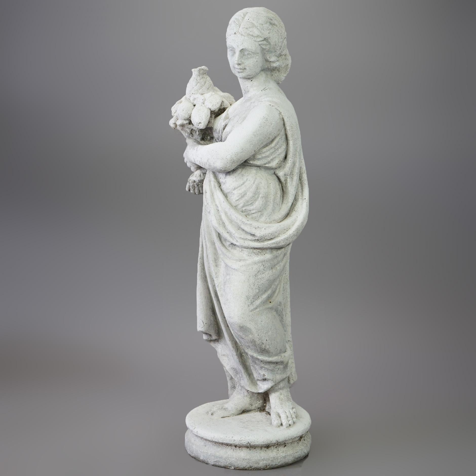 A figural garden statue offers cast hard stone of a Classical woman with flowers, 20th century

Measures- 30''H x 10.5''W x 9''D.
