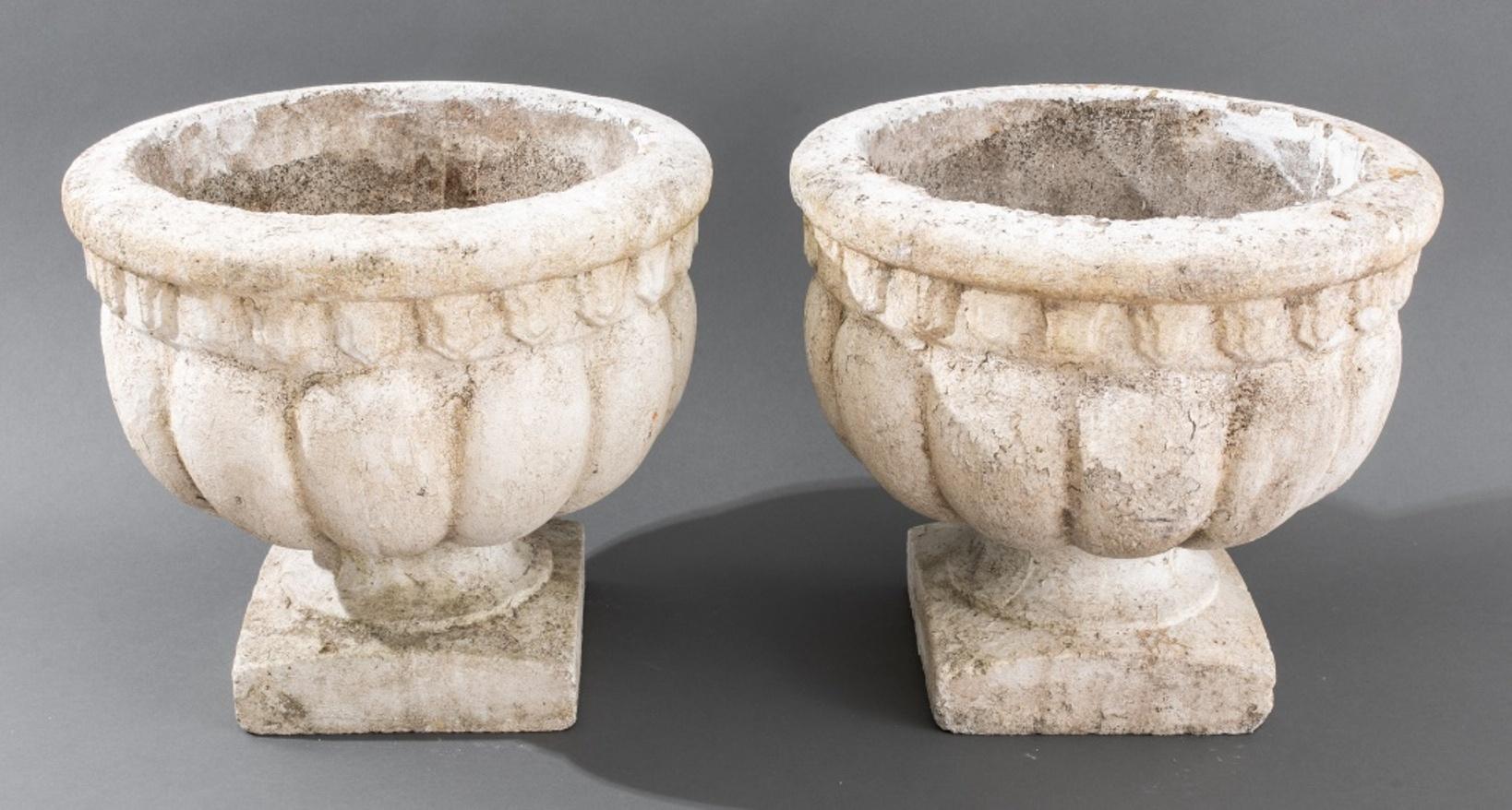 Classical Manner White Painted Cast Stone Urns, a pair, 20th century, with gadrooned sides and flaring lip above a socle on square base.

Dimensions: 13