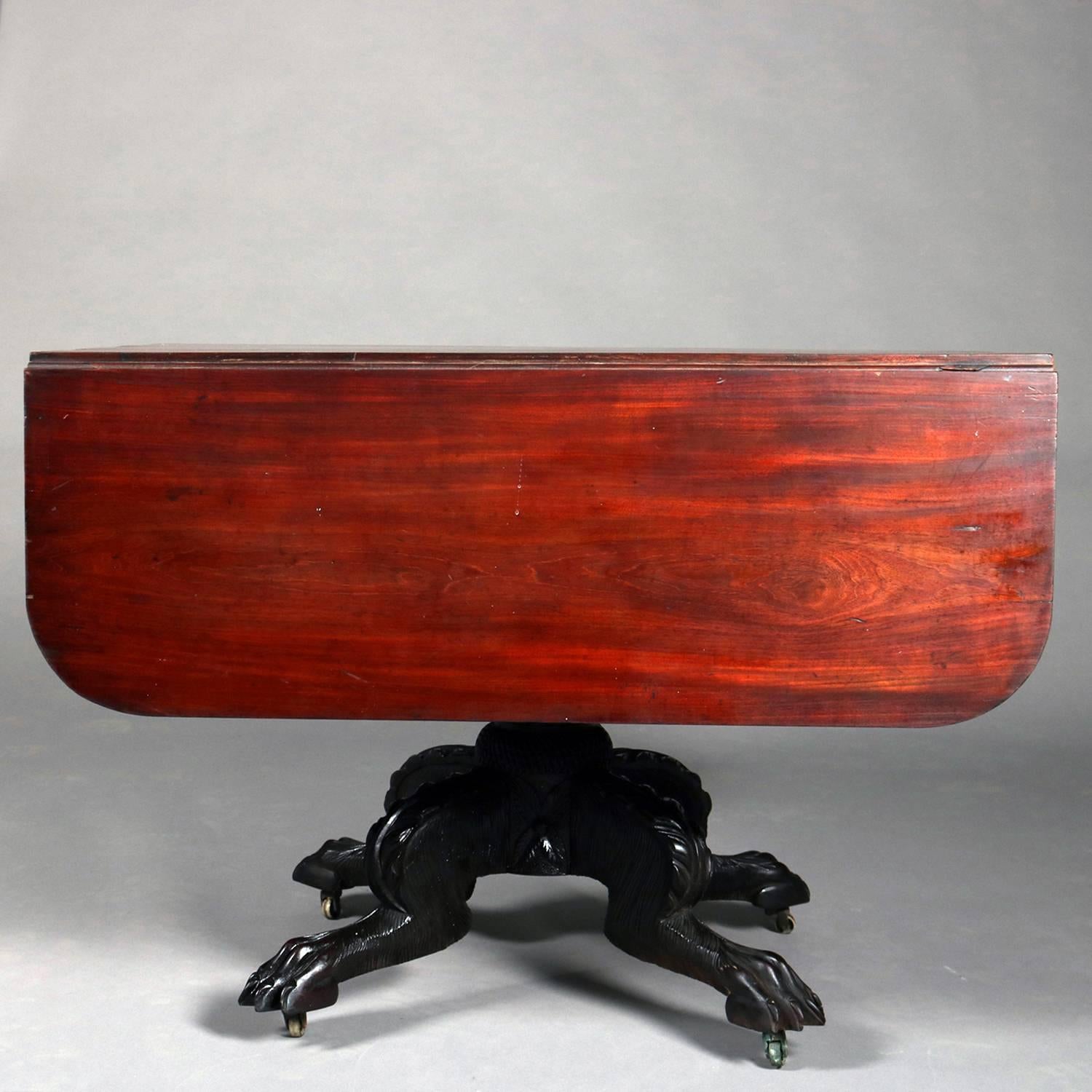 Antique classical Meeks school American Empire flame mahogany drop leaf table features acanthus carved pedestal seated on four fur carved legs terminating in paw feet with casters, circa 1840.

Measures: 28
