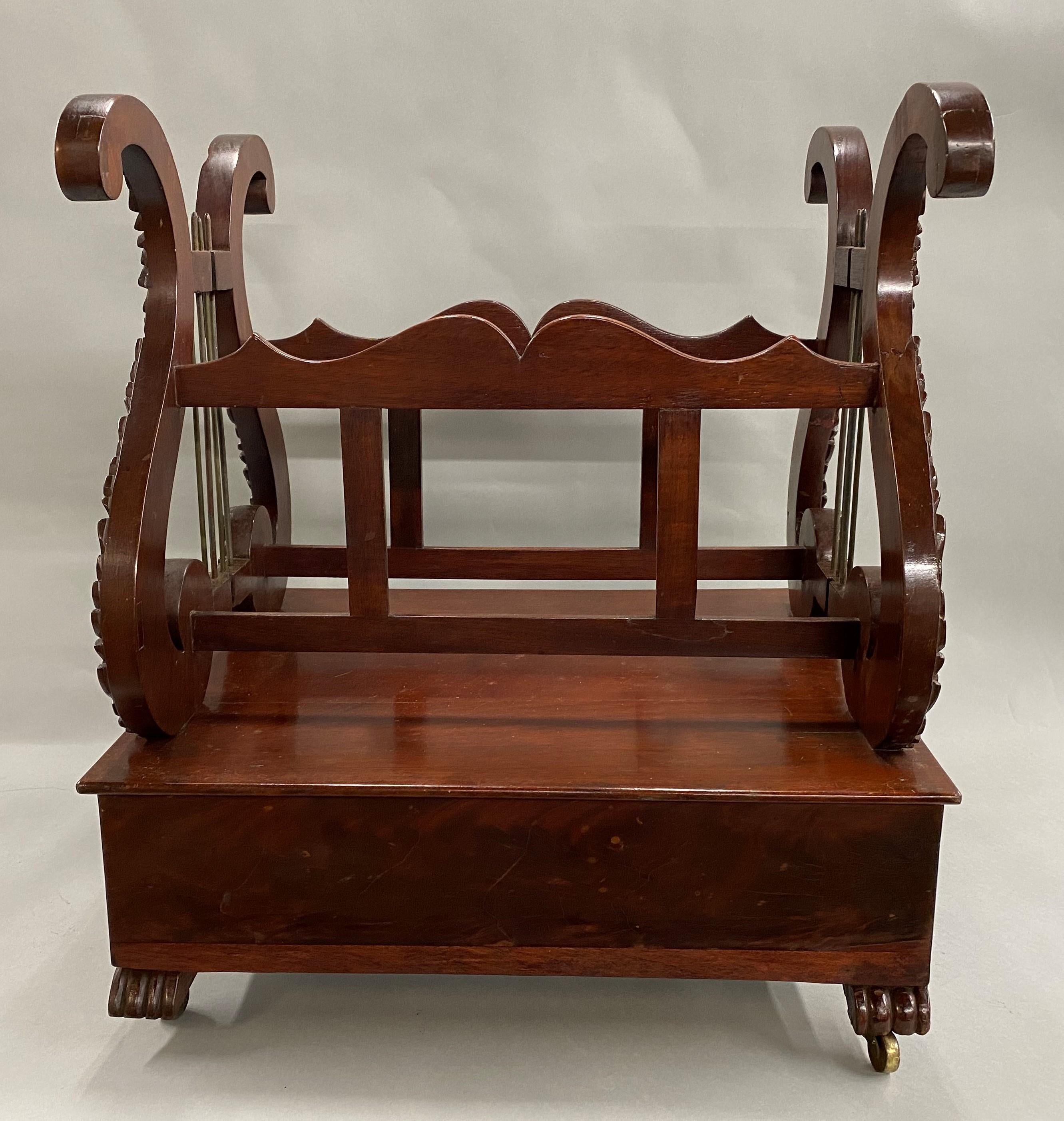 A fine classical Empire Canterbury, featuring heavily carved lyre ends with rosettes and brass strings, with nicely shaped stretchers above a crotched mahogany veneered case fitted with one long drawer and one false drawer facade all raised by four