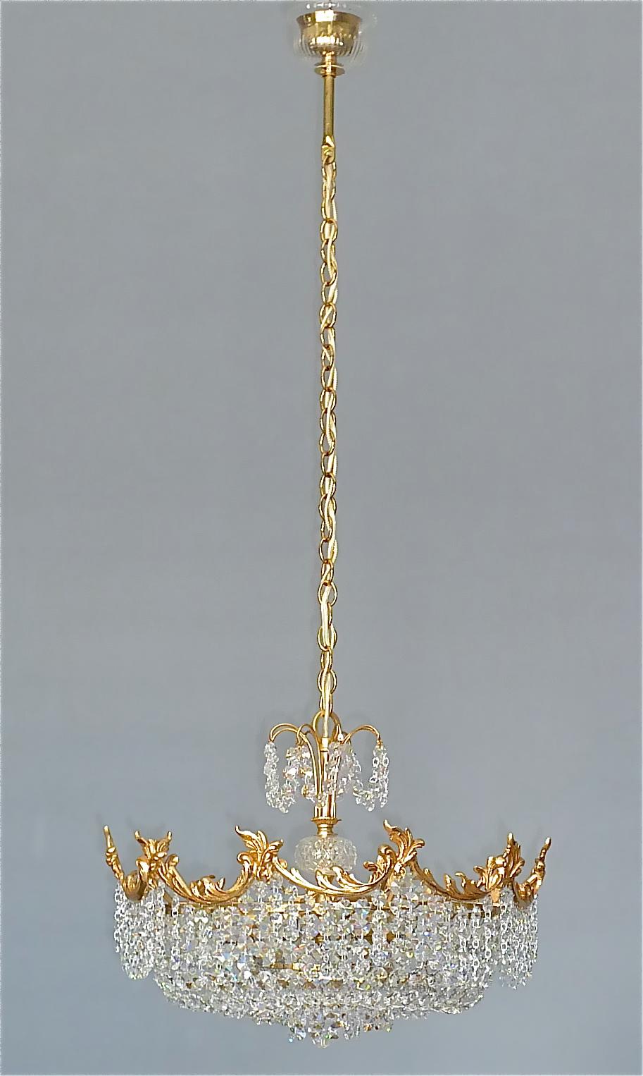 Fine classical Rococo style multi-tiered gilt brass and crystal glass chandelier made by Palwa, Germany circa 1960. The Hollywood Regency chain-hanging length-adjustable chandelier has a wonderful floral rococo baroque style outer rim and lots of