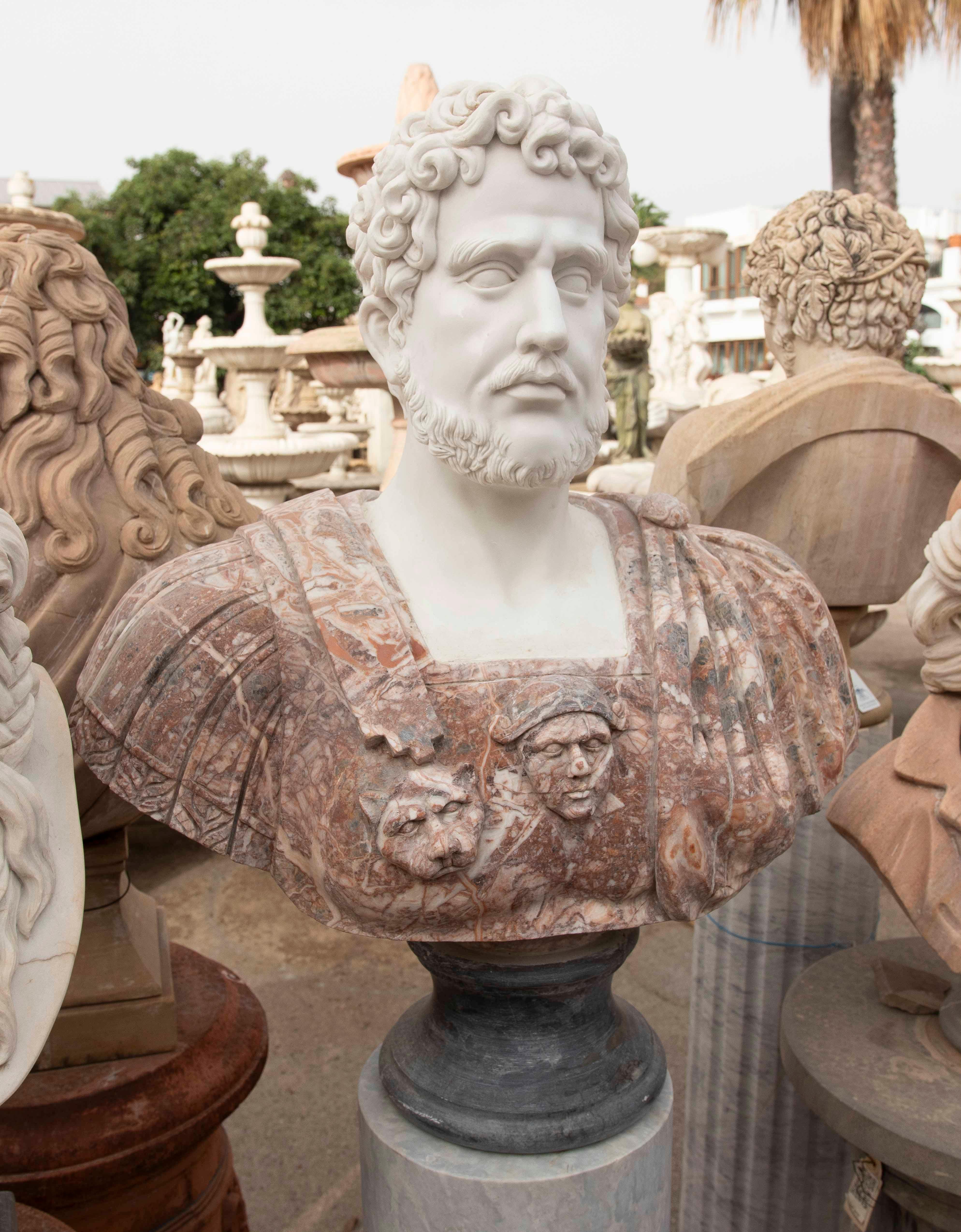 Magnífico busto de un emperador romano con rostro de mármol blanco y torso de mármol rojo veteado. La armadura presenta relieves decorativos de cabezas y motivos clásicos que le confieren carácter y autenticidad. La calidad de la talla se refleja en