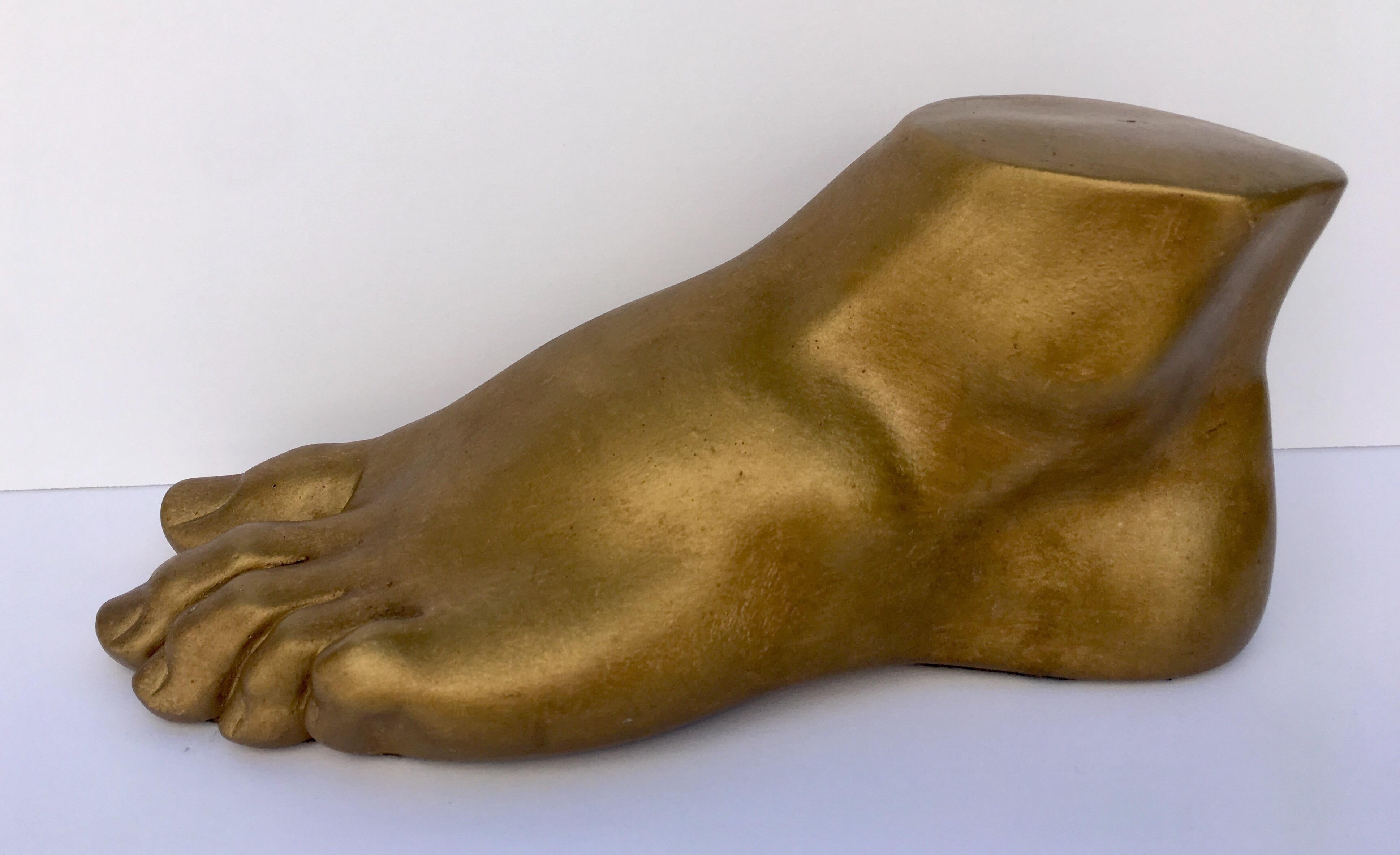 Neoclassical style plaster cast foot fragment sculpture featuring a patinated gold metallic finish. An interesting tabletop accessory for any Hollywood Regency interior.