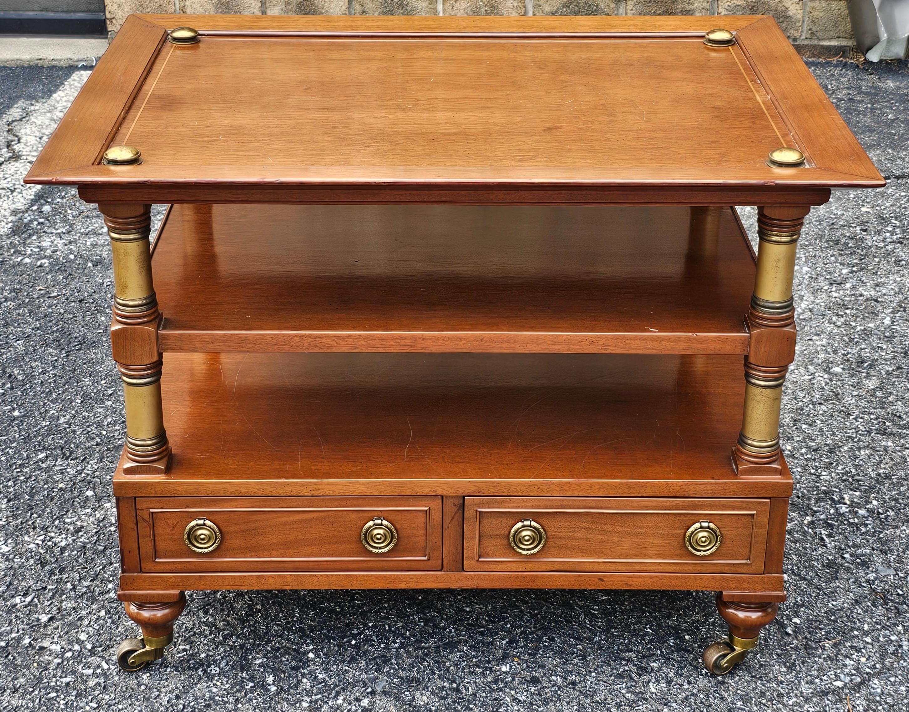 Mesa auxiliar de tres niveles de caoba y latón, de estilo clásico.
Mide 29,5