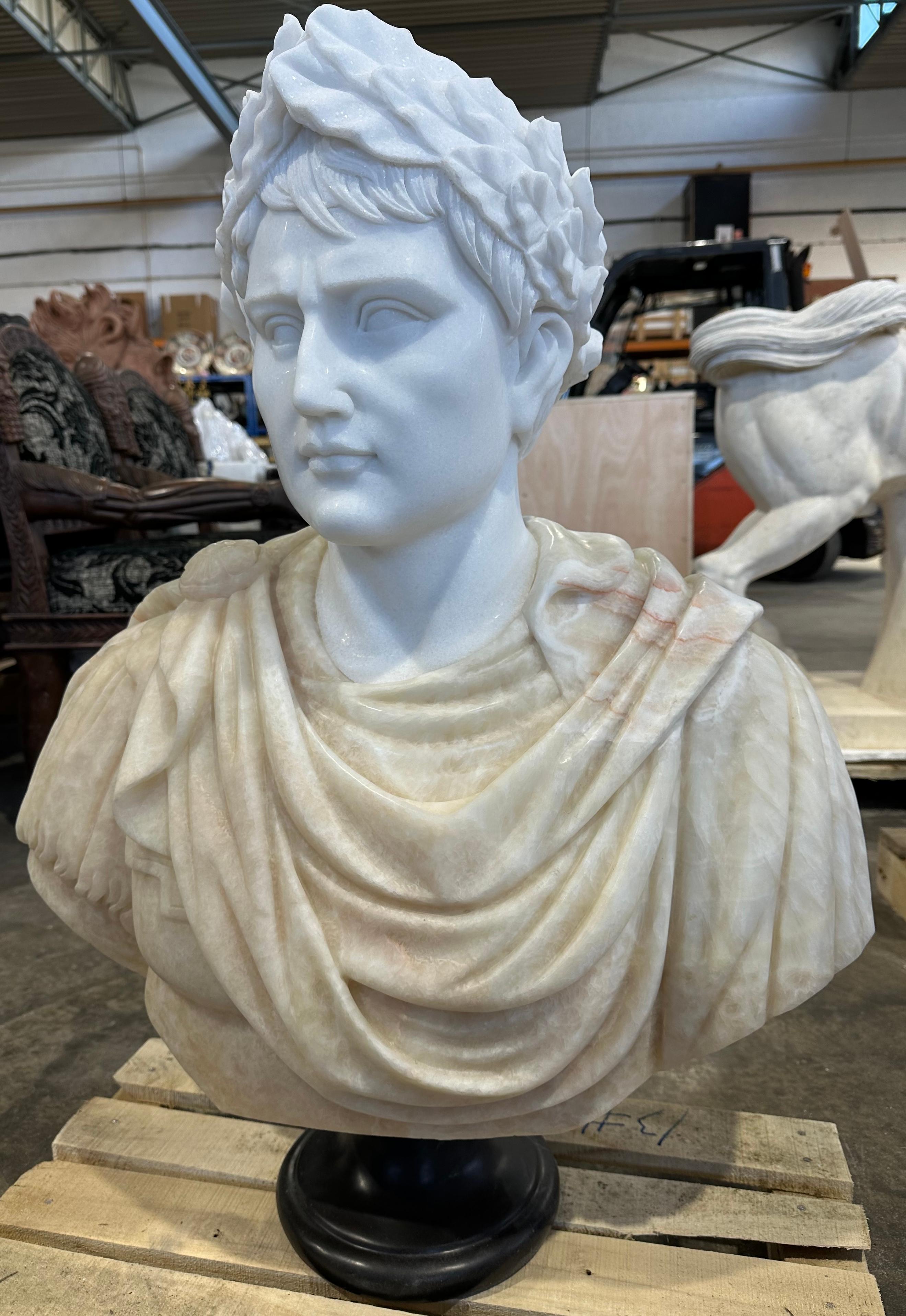 A impressive beige and white marble male bust. A grand and imposing figure with detailed carving to the face, hair, garments and breastplate. A hand carved wreath suggests someone of great importance. The figures profile is skilfully carved with