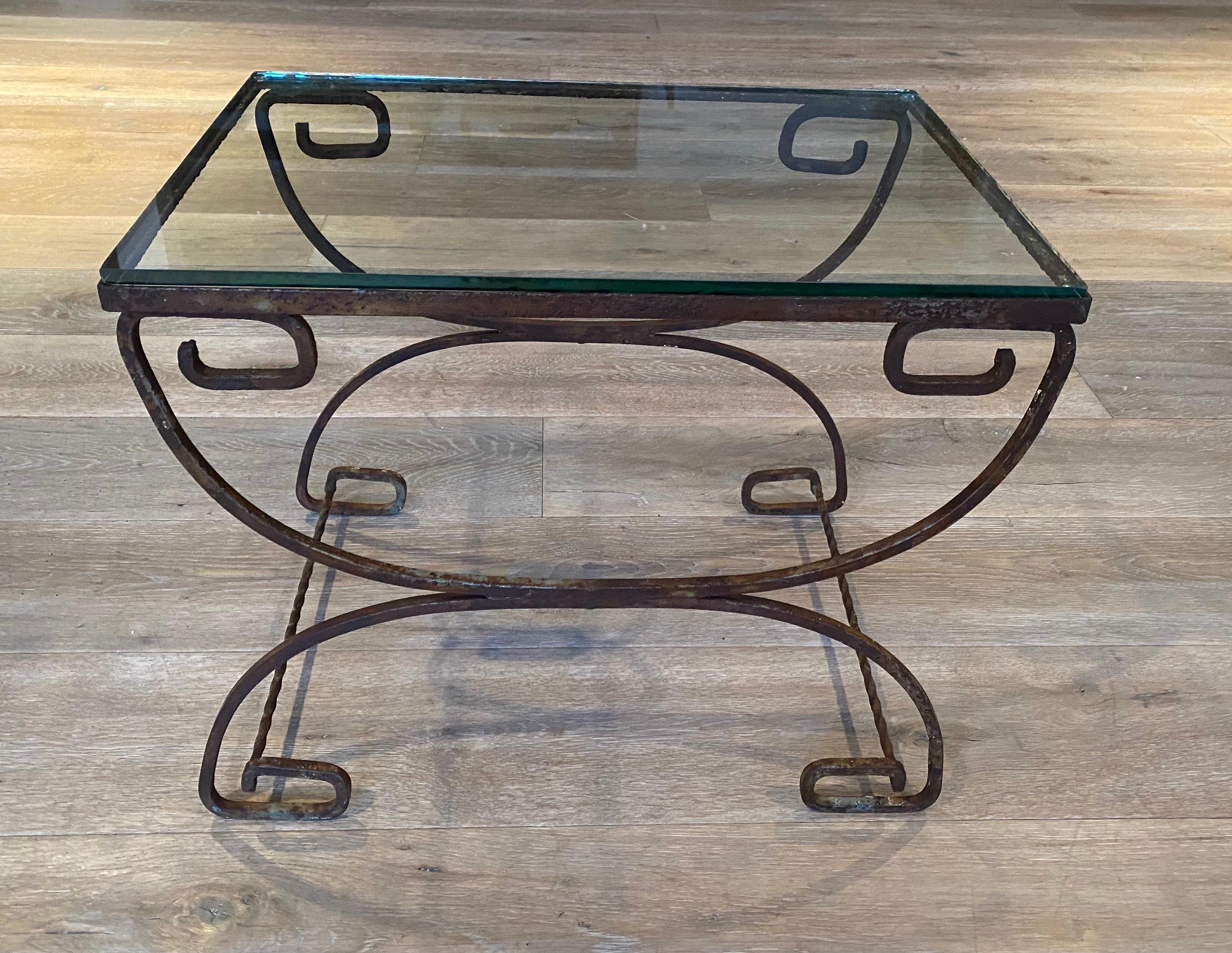Une table en fer forgé de style classique avec un plateau en verre épais. Convient à un usage intérieur ou extérieur.