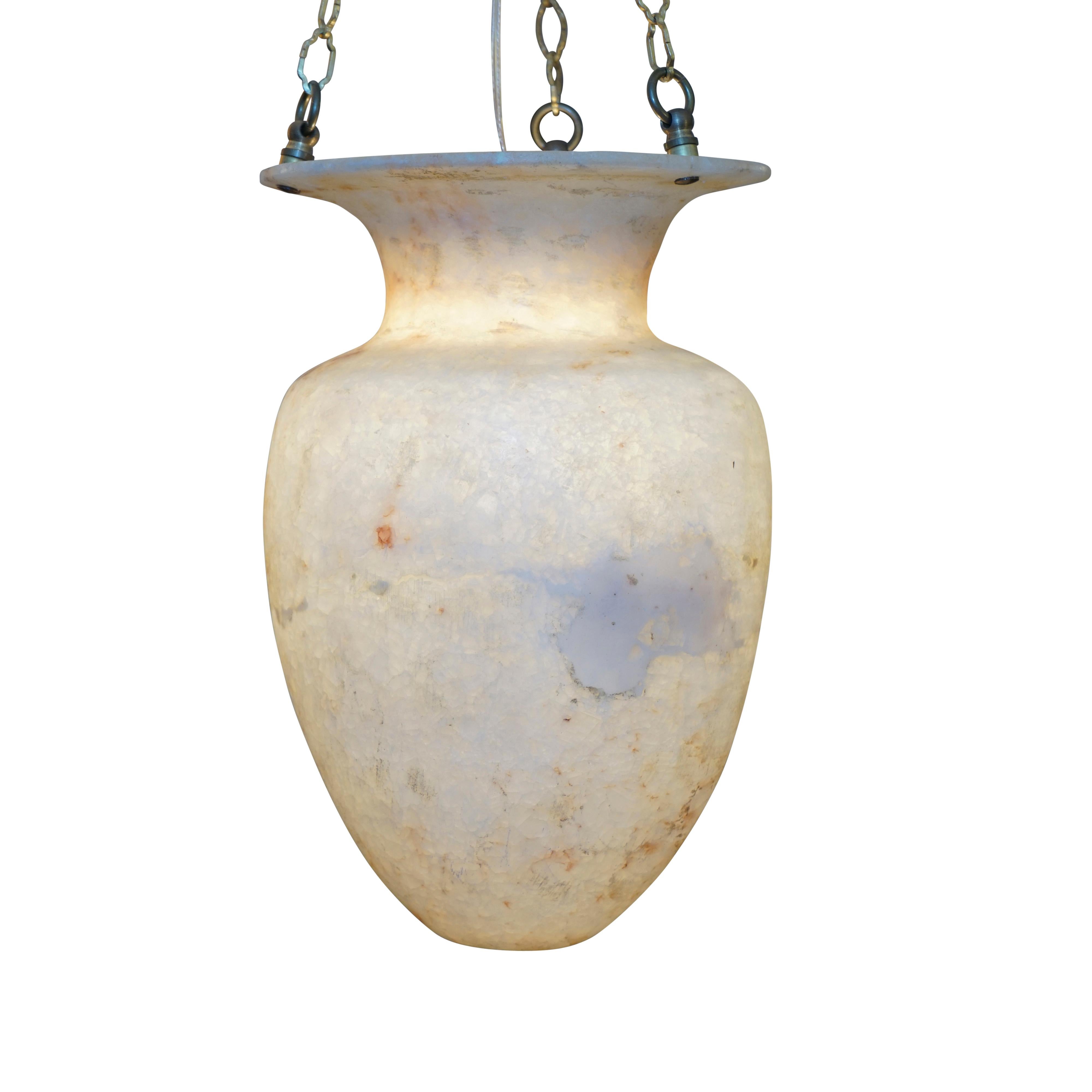 Carved of a unique crystalized cream and gold alabaster, this Amphora shaped light fixture reflects the artist's fascination with creating a vessel using electricity with an ancient material and ancient form. Recently rewired, this light fixture