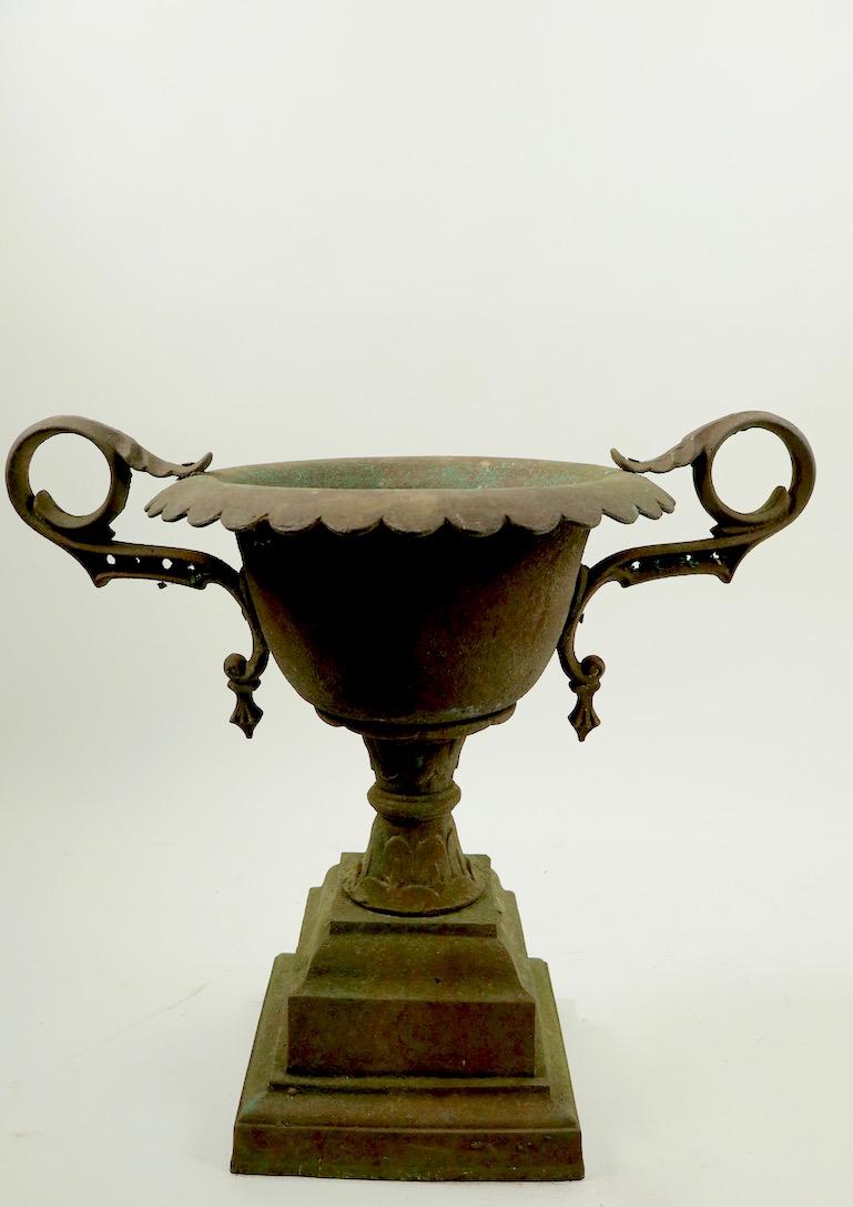 Victorian cast iron urn planter with dramatic handles. The urn has beautiful original patinated finish. Diameter with handles 32 x 12 interior D x 20 D w/o handles x 26 H to top of bowl . Base 20 x 20 inches. Probably Mott or Fisk iron works