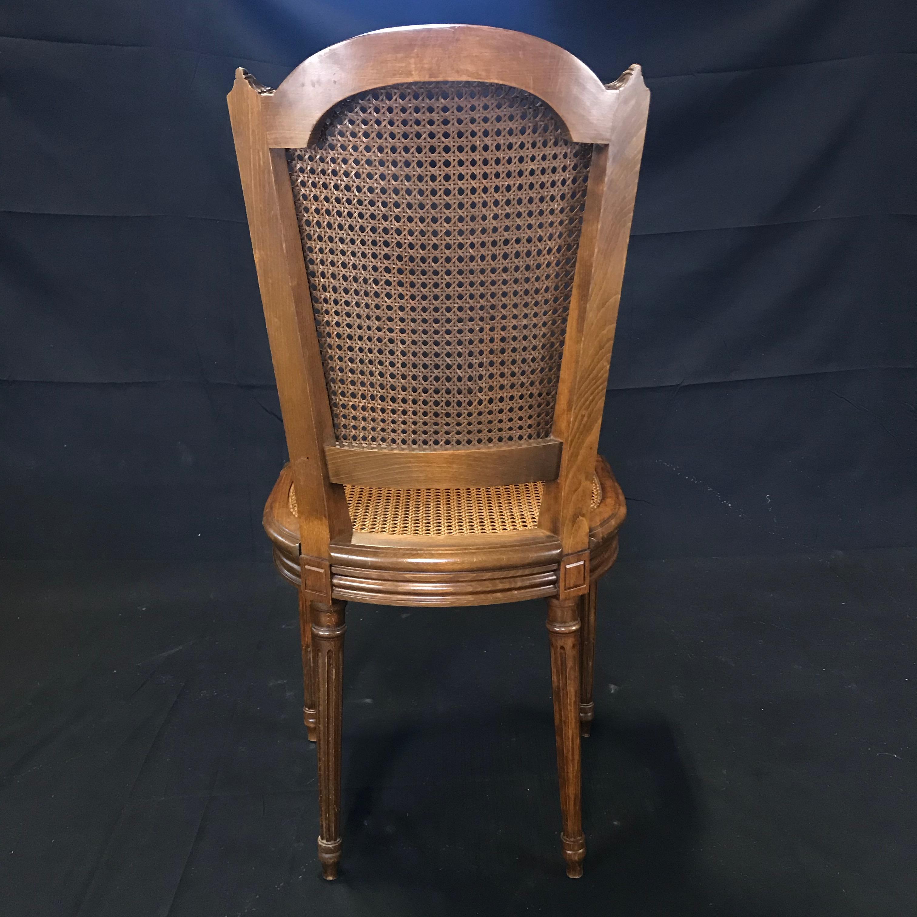 A classically beautiful set of French Louis XVI style chairs, bought in Lyon, France having cane backs and seats, light walnut frames, reeded tapering legs and handsome carved wood details. One cane seat has very minor damage on the front of the