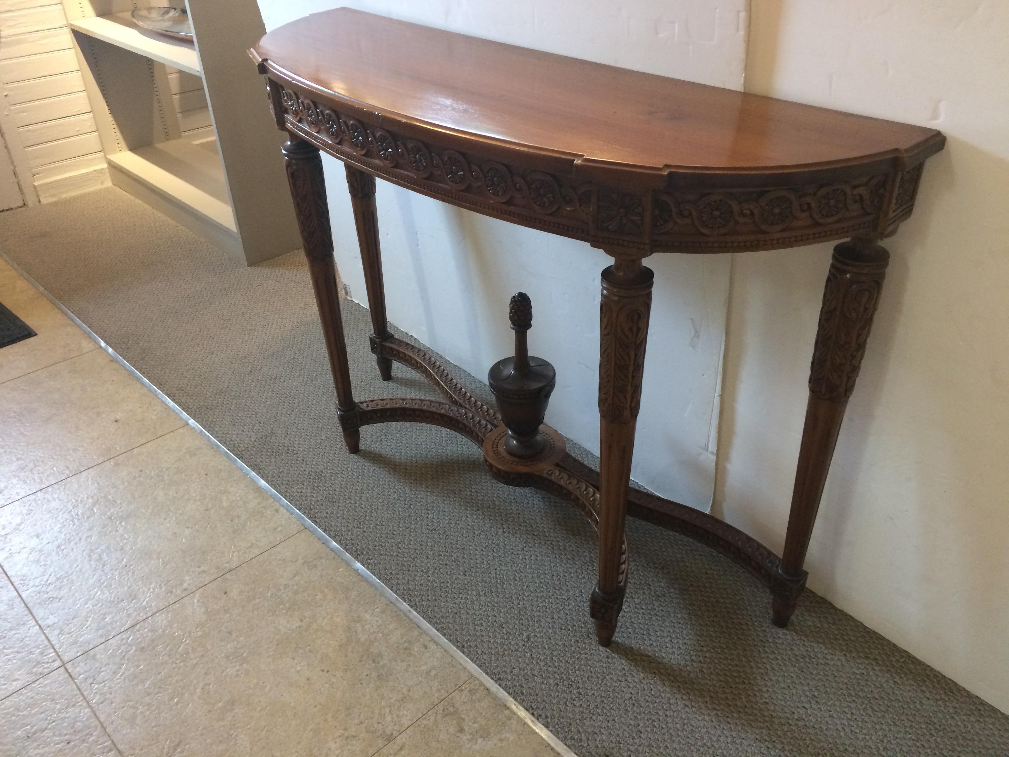 Beautiful narrow carved walnut antique demilune console having gorgeous decorative florets on the apron, reeded elegant legs, and an impressively large urn that rises from the lovely stretcher base at the bottom.