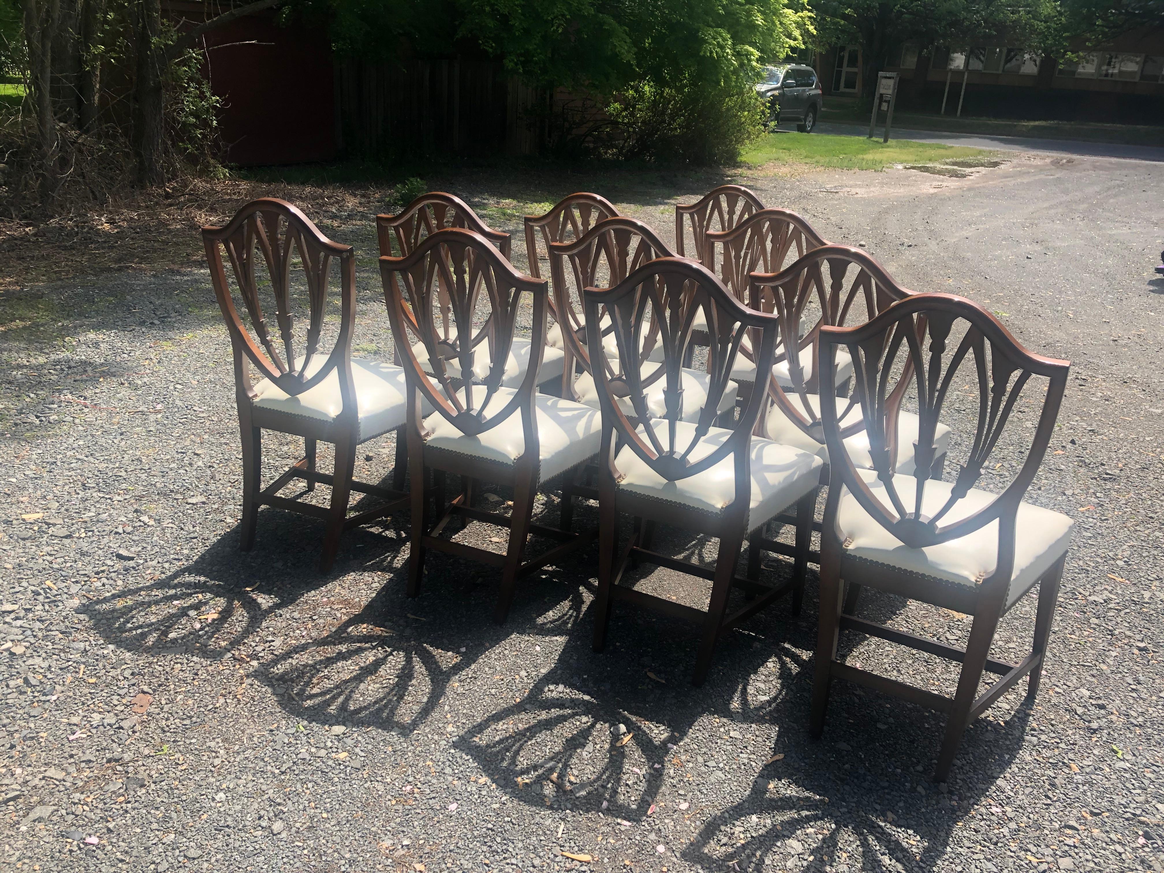 Magnificent set of 10 hand crafted mahogany Hepplewhite style side dining chairs by Virginia Craftsman having bellflower and sunburst details, shield backs, tapered legs, and glamorous white leather seats with brass nailheads.