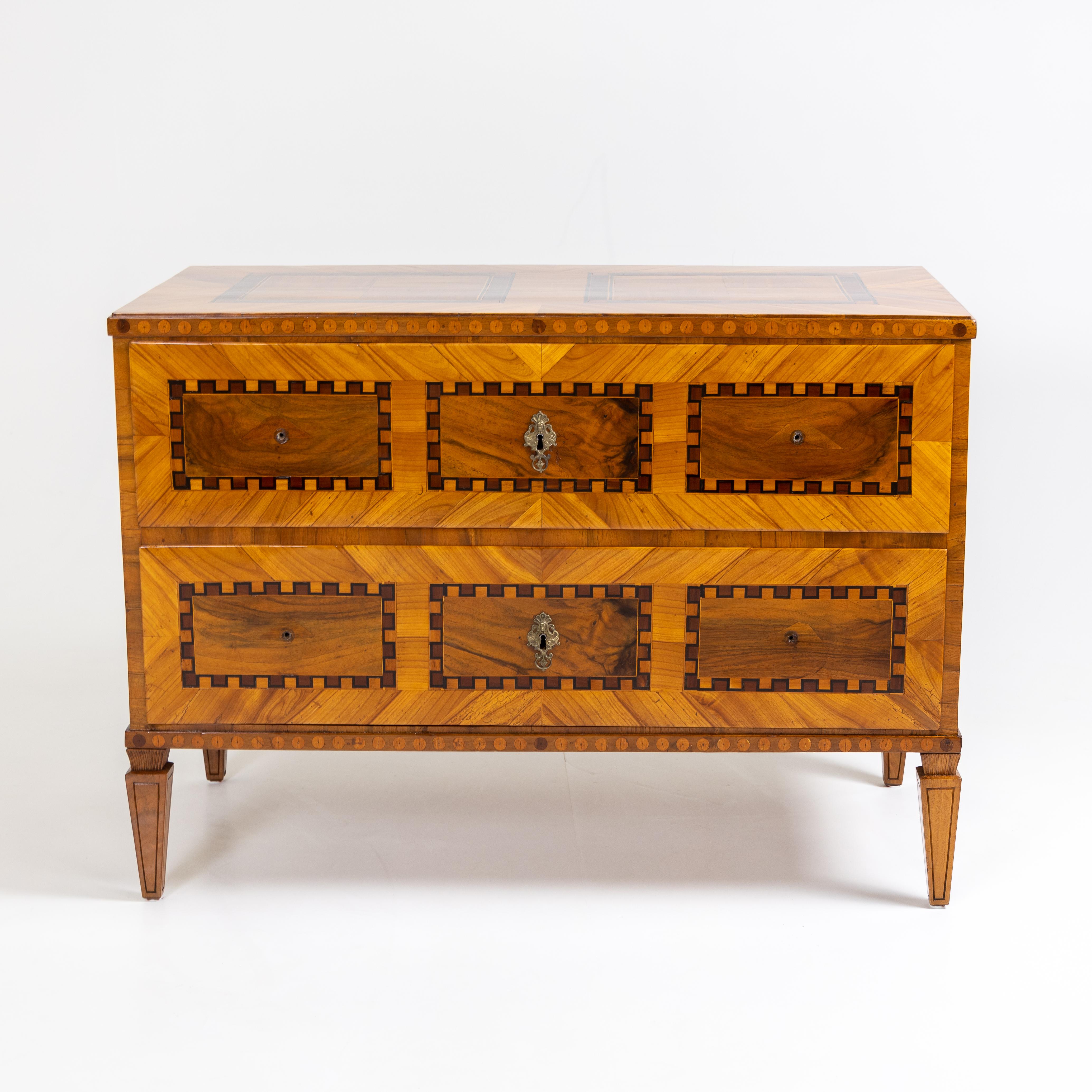 Classicistic two-bay chest of drawers on square pointed legs. Walnut and plum, veneered. The chest of drawers was expertly restored while preserving the patina.
  