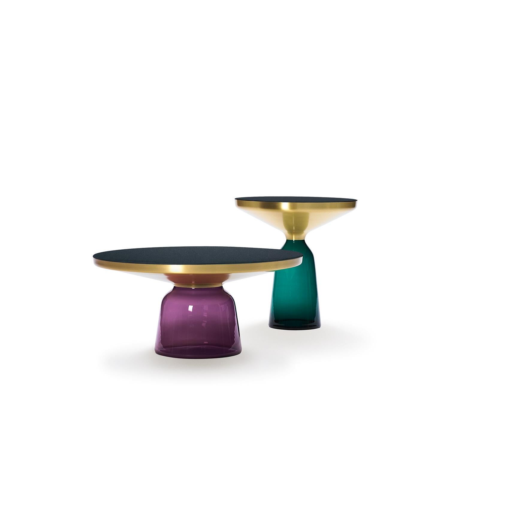 La table Bell de Sebastian Herkner bouleverse nos habitudes de perception en utilisant le matériau léger et fragile qu'est le verre comme base pour un plateau en métal qui semble flotter au-dessus. Soufflé à la main de manière traditionnelle à