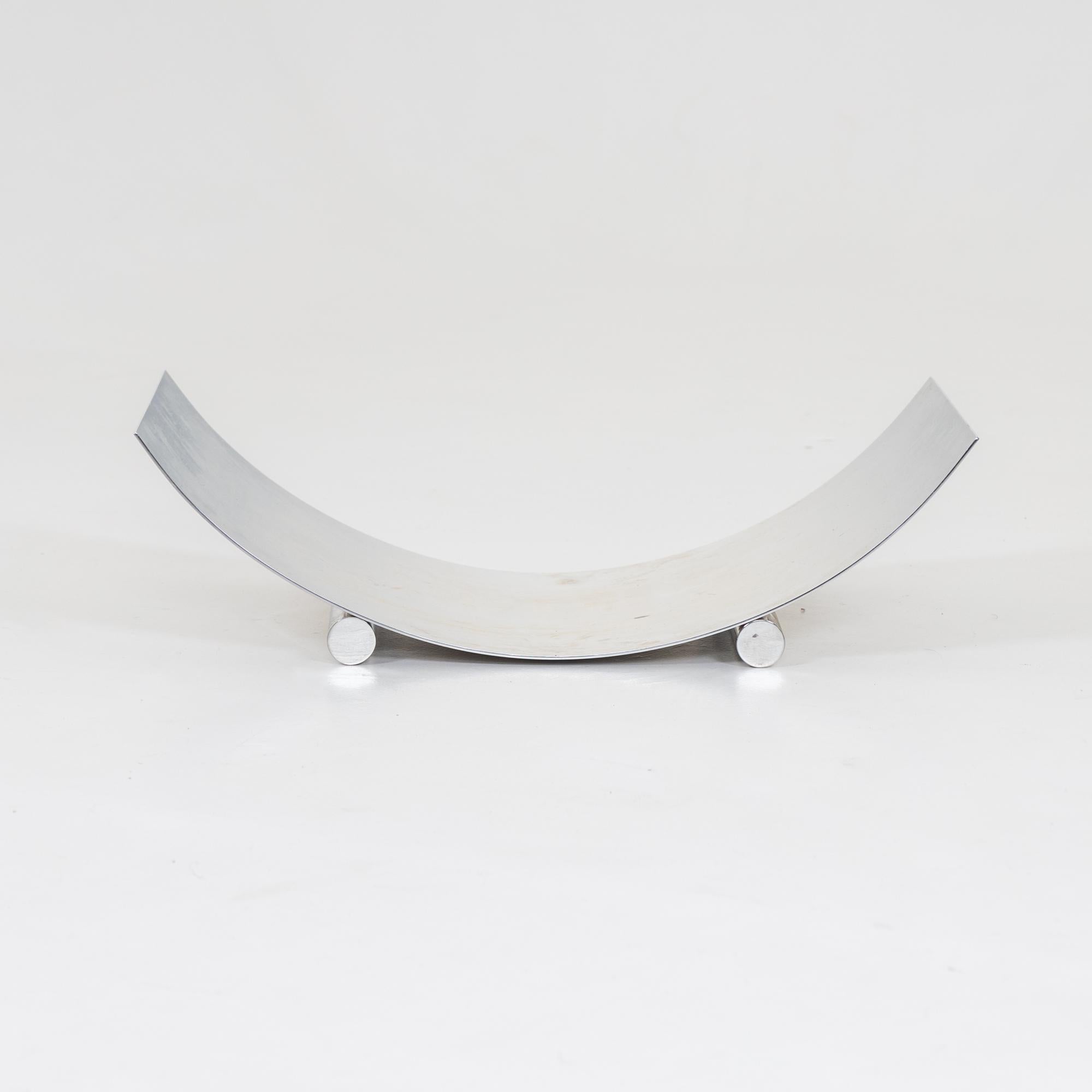Elegant polished steel bowl for firewood with curved surface and cylindrical feet. Stamped on the rim ClassiCon 1191.