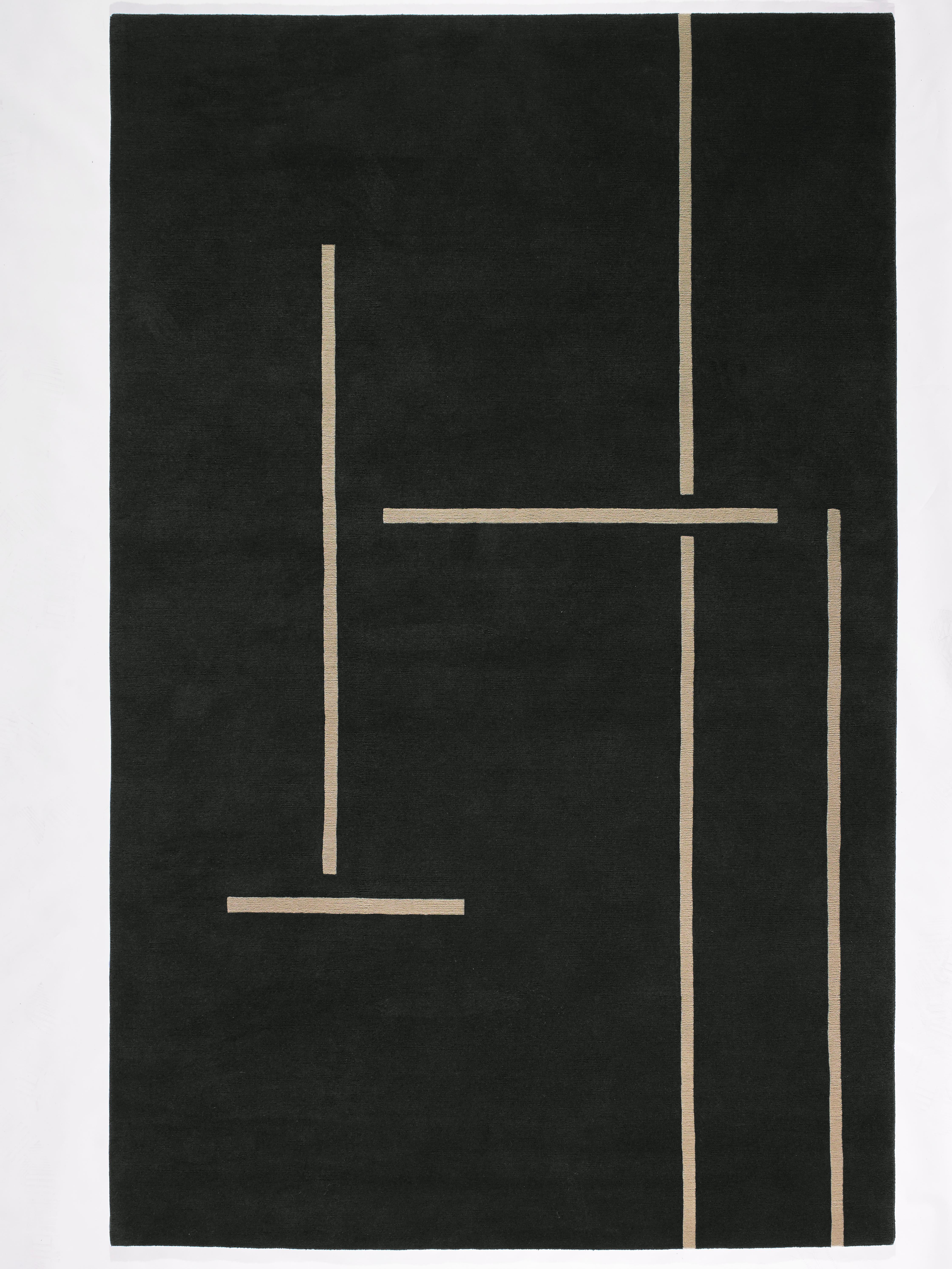 Monolith is characterised by beige horizontal and vertical lines of varying lengths that elegantly accentuate the earthy dark grey background. In places, the lines cross without touching - they suggest a structure that seems to divide the rug into