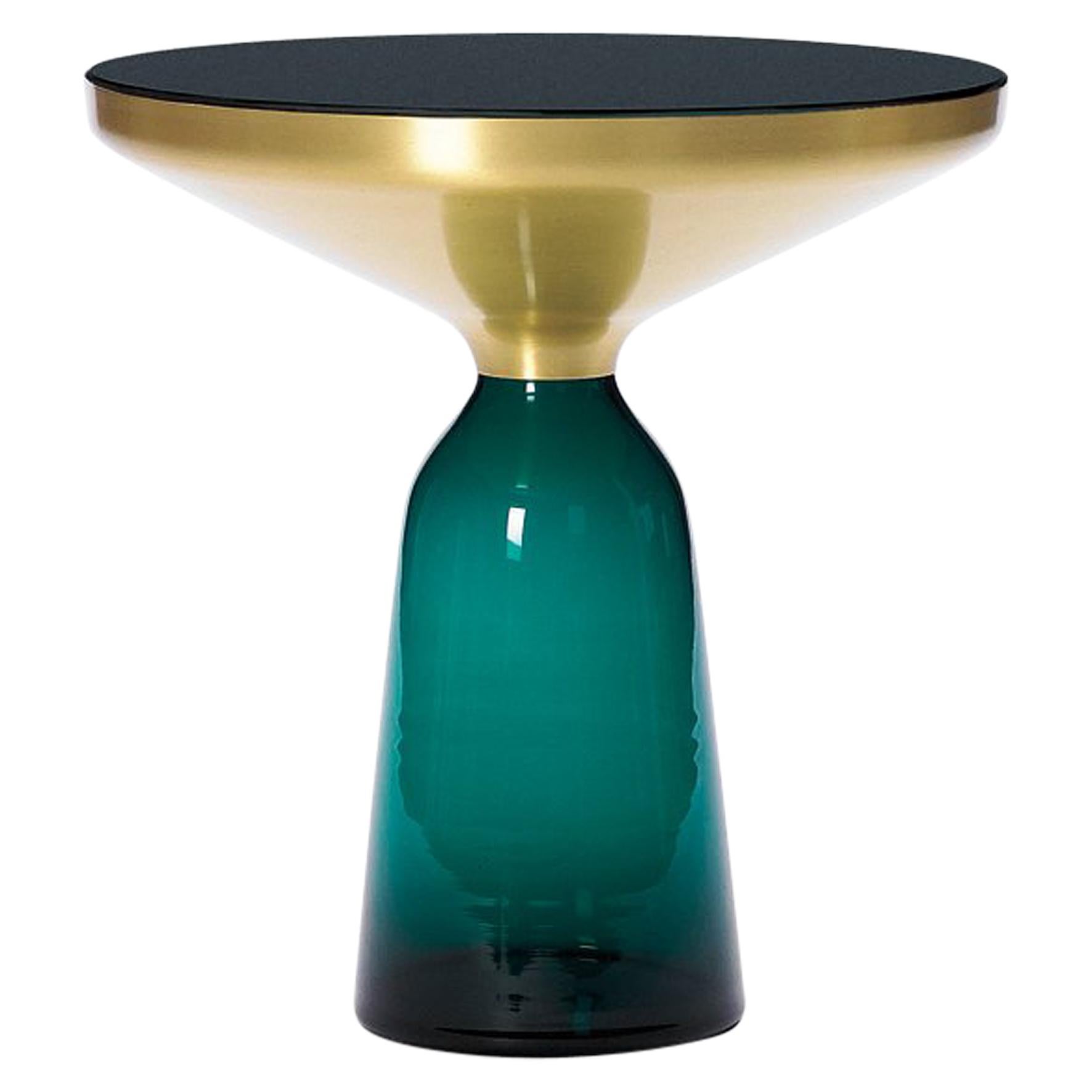 La table Bell de Sebastian Herkner bouleverse nos habitudes de perception en utilisant le matériau léger et fragile qu'est le verre comme base pour un plateau en métal qui semble flotter au-dessus. Soufflée à la main de manière traditionnelle à