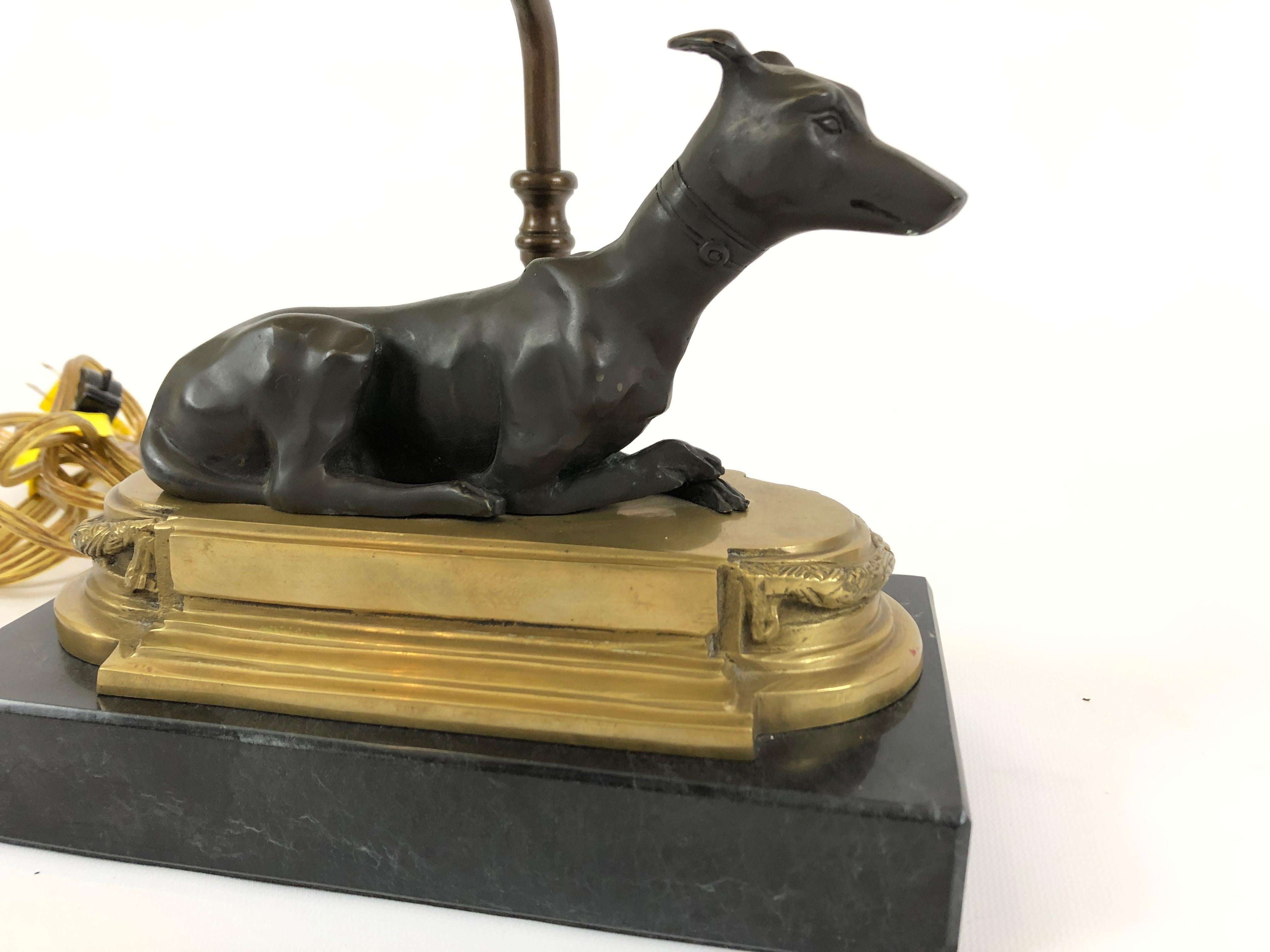 A wonderfully sculptural table or desk lamp having a bronze greyhound dog resting on chunky brass and wood base, stylishly designed custom shade and neoclassical brass finial to top it off.