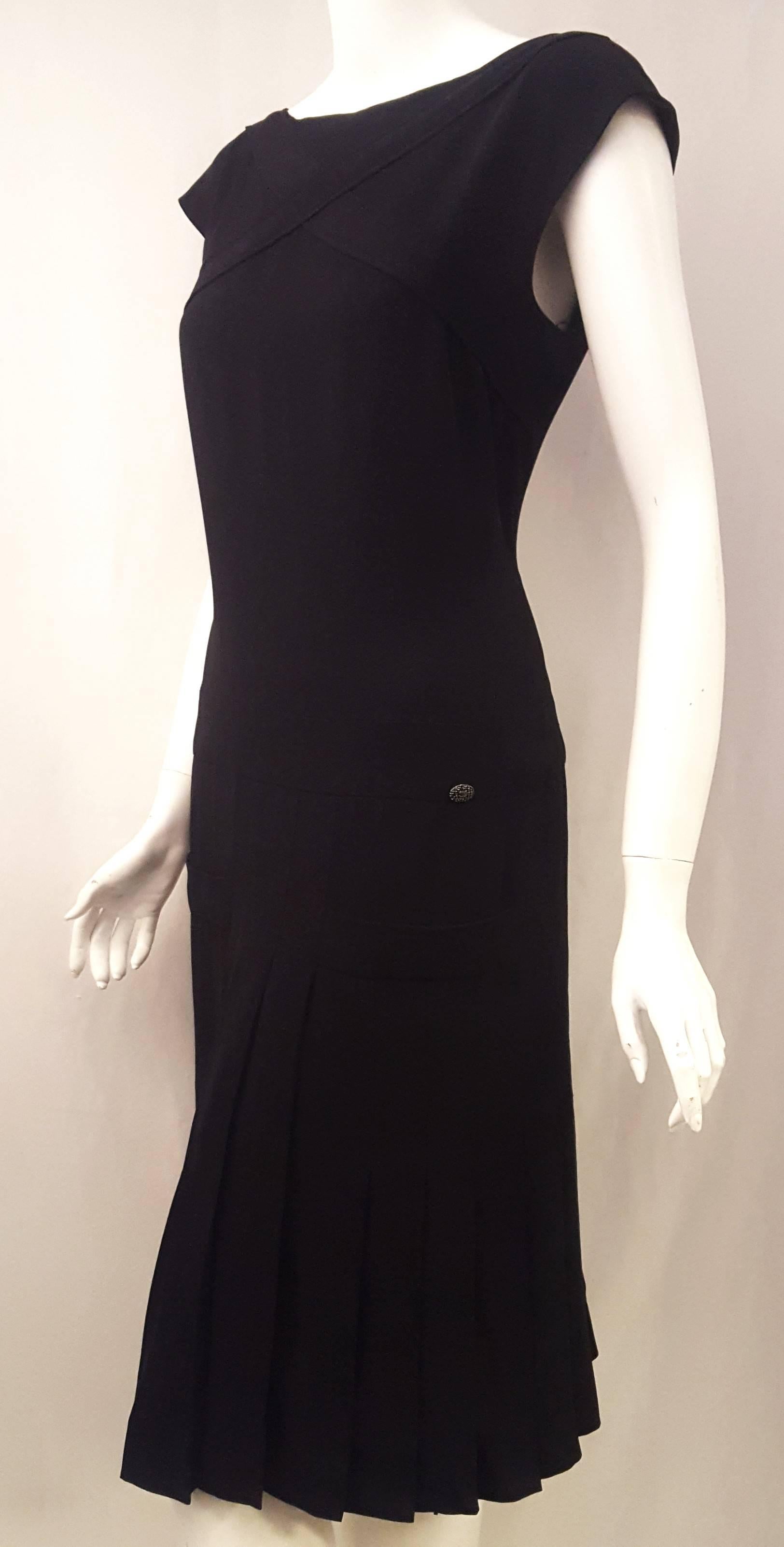 This Chanel black silk dress is a classic.  The top of this dress contains a crisscross detail at the chest and a hidden zipper at the back for closure and features a drop waist and a pleated skirt.  The drop waist is given prominence by a band,