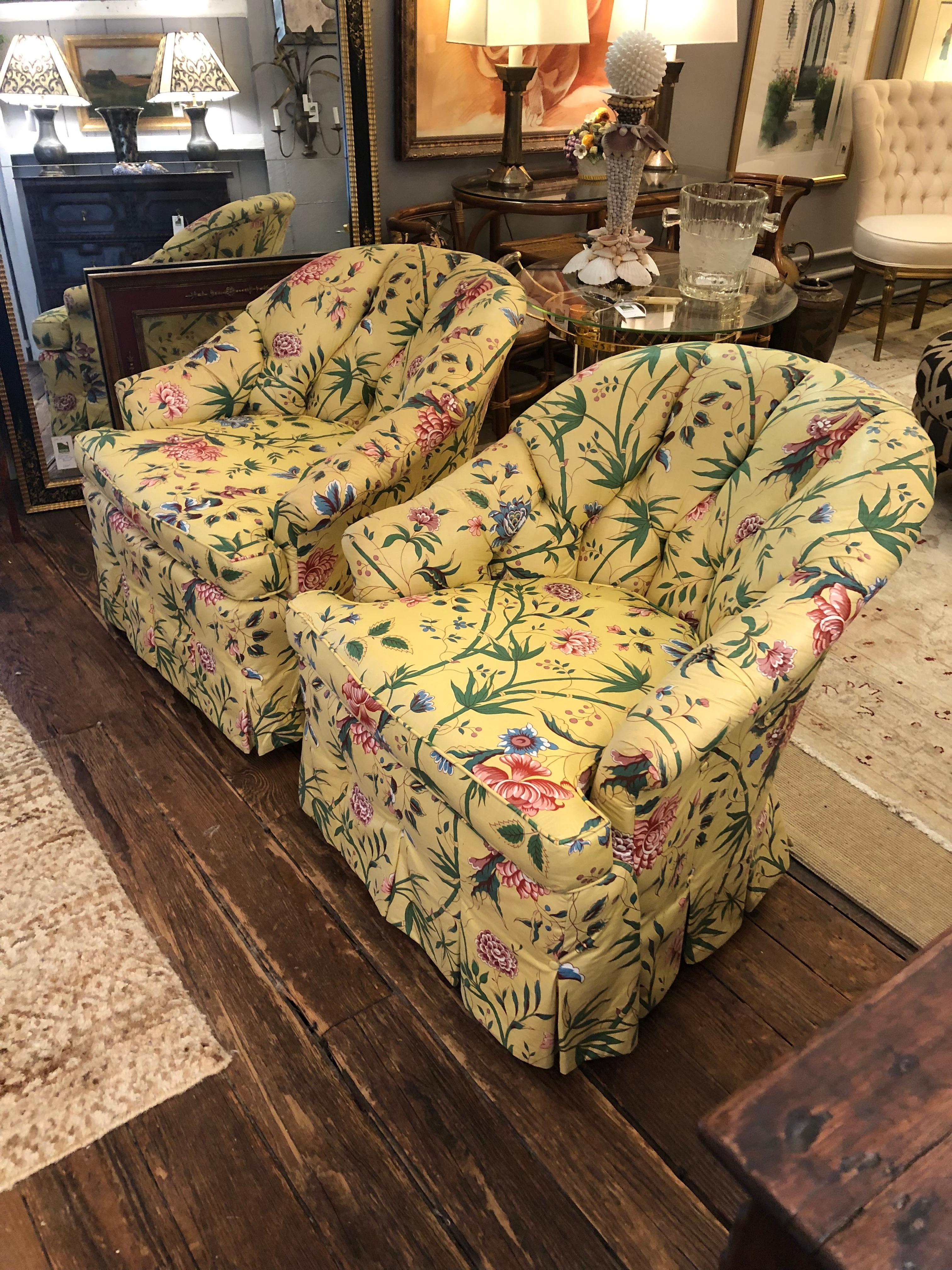 Classy comfy pair of yellow floral chintz upholstered club chairs having box pleats at the bottom with decorative buttons and tufted interior backs. 
seat depth 23
arm height 24.