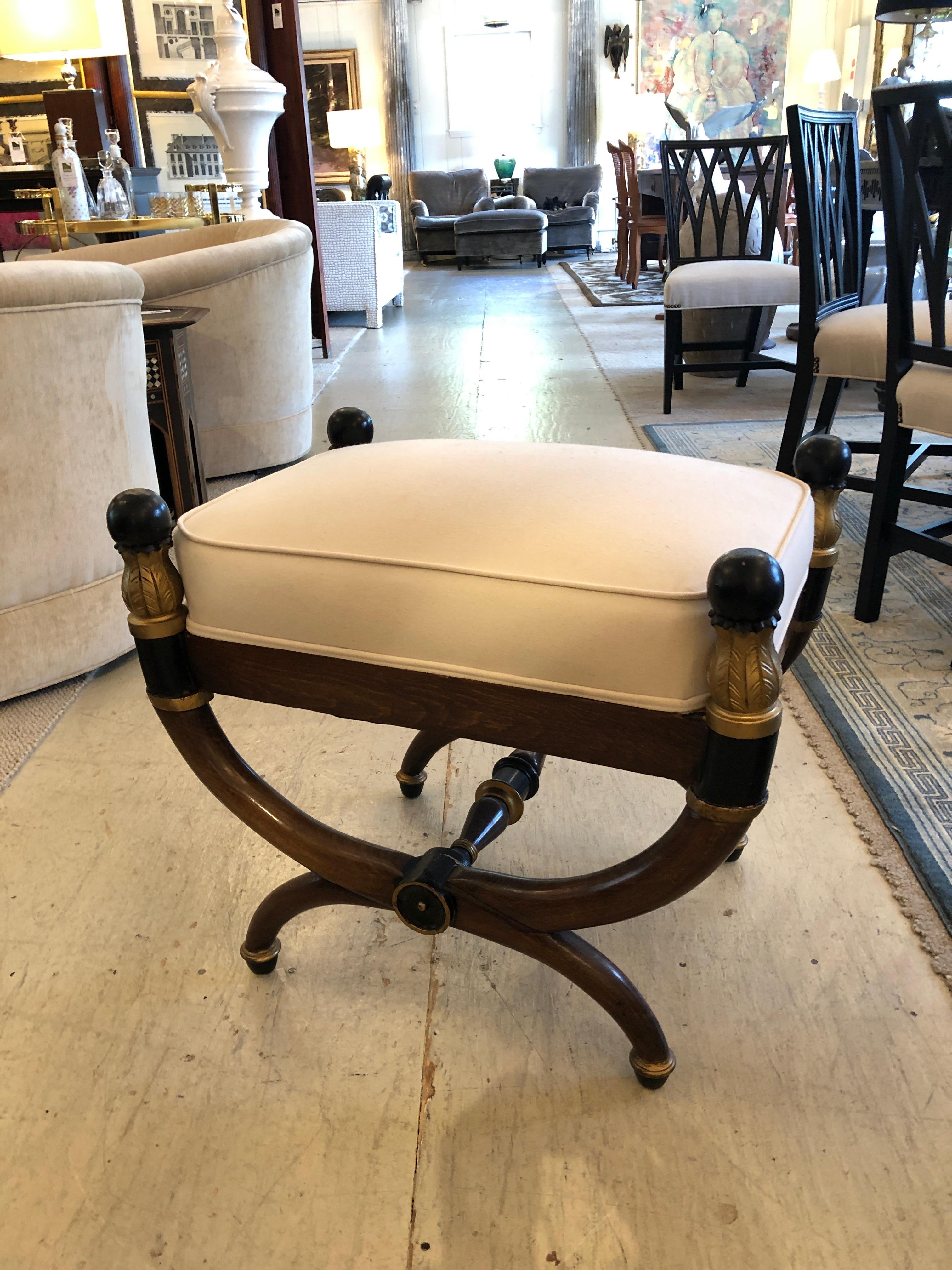 Rich looking antique mahogany Empire style bench or ottoman having ebonized and gilded decoration and a crisp heavy gauge cotton duck attached seat cushion.