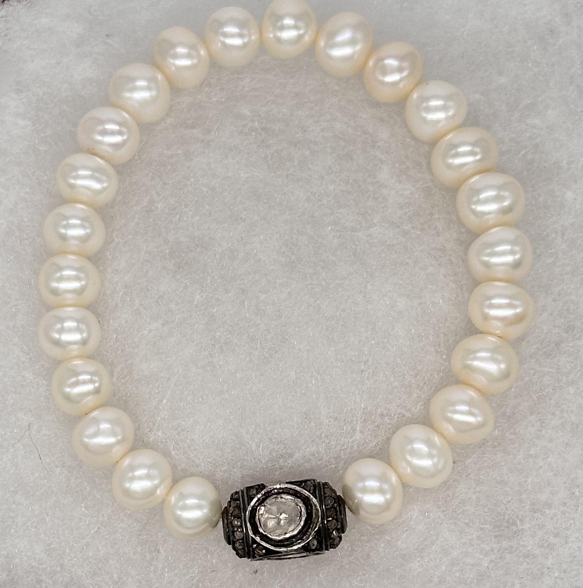The bracelet is an elegant piece of jewelry, featuring a classic stretch design for easy wear. It is composed predominantly of lustrous freshwater white pearls, each with a smooth, radiant surface and a delicate, uniform size, exuding timeless