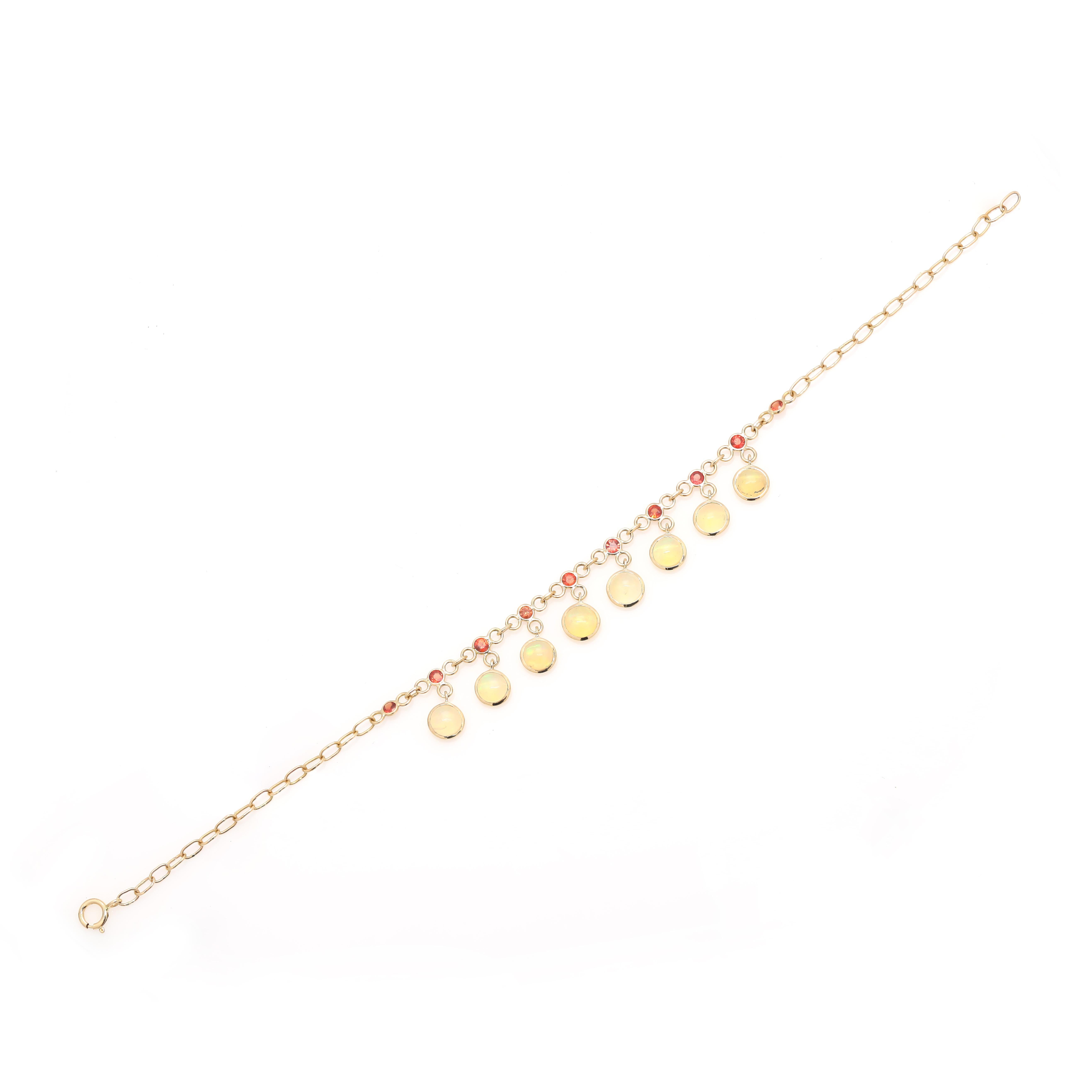 Ce bracelet pendentif en chaîne saphir orange opale en or 18 carats met en valeur 18 saphirs et opales naturels étincelants à l'infini, d'un poids de 3,08 carats. Il mesure 7.5 pouces de long. 
Conçue avec un saphir orange de taille ronde formant