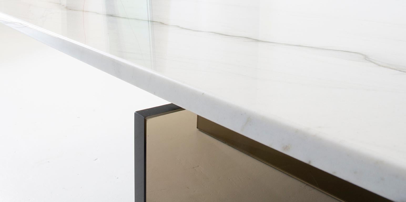Une dalle de marbre semblant flotter au-dessus d'une base en verre ultra-clair ou bronzé. En façonnant à la main la face inférieure de la dalle de marbre, cet effet de flottement est un geste simple qui rehausse le design de manière subtile mais