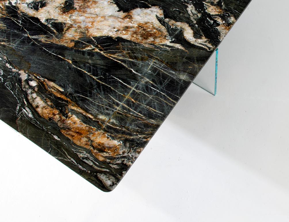 A slab of marble appearing to float above a base of ultra-clear or bronzed glass. By hand shaping the underside of the marble slab this floating effect is a simple gesture that elevates the design in a subtle yet compelling manner. Available in