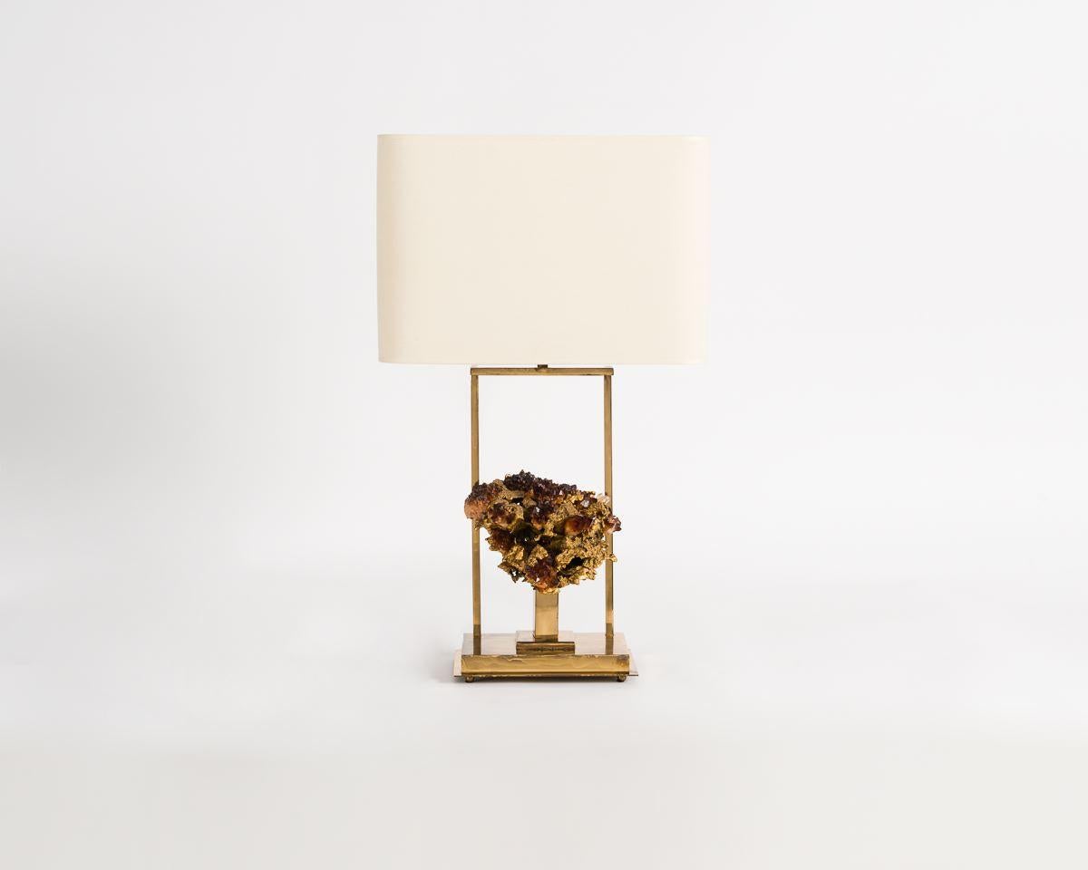 La lampe de table de Claude Boeltz oppose les lignes épurées et mécaniquement sculptées du laiton à la beauté asymétrique et numineuse des objets naturels. La fonction de cette pièce est presque supplantée par sa forme, car la lampe sert également