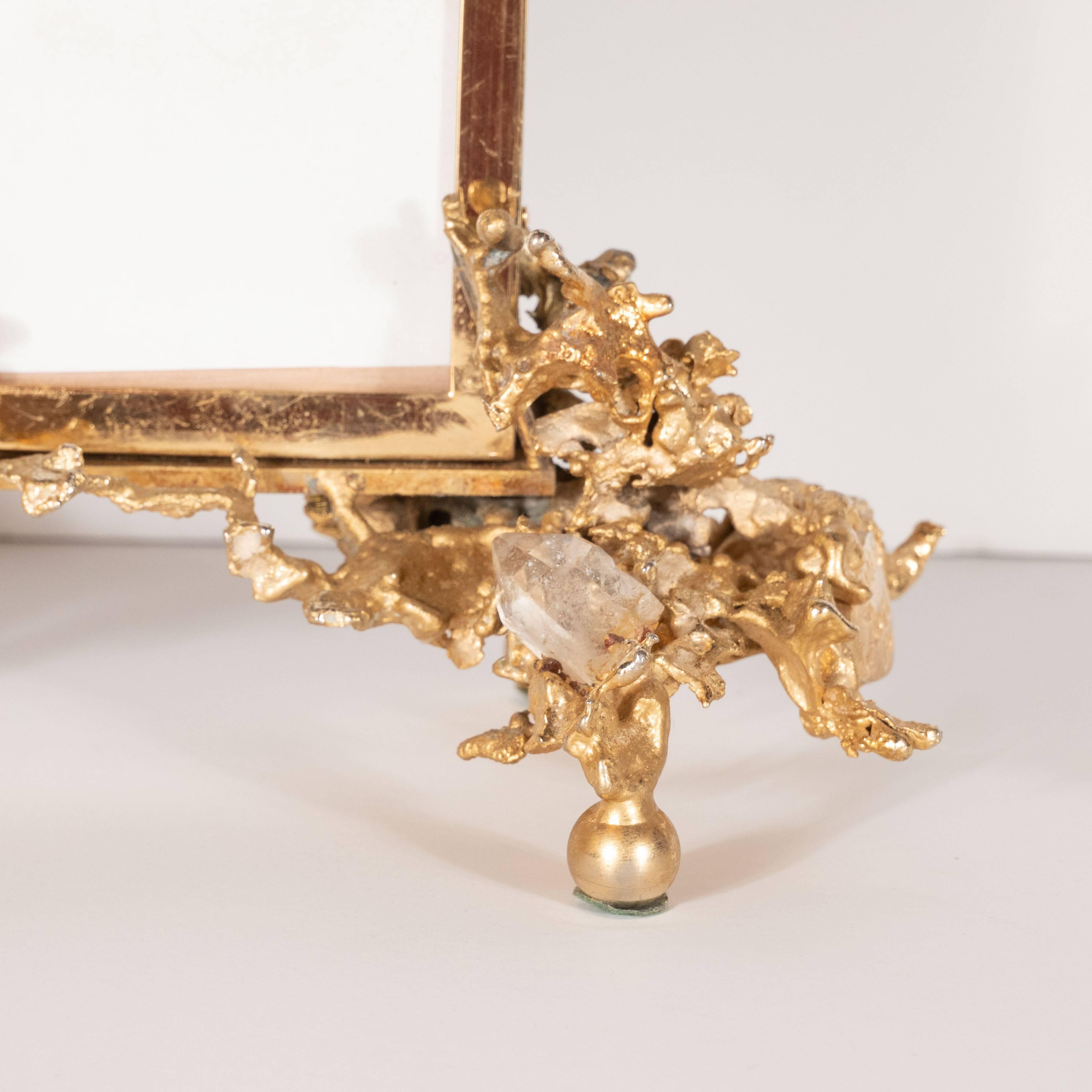 This unique and captivating modernist picture frame was realized by the esteemed midcentury artist Claude Victor Boeltz, circa 1970. It features an exploded, liquid- like form created using 24 karat gold bronze with prismatic clusters of natural